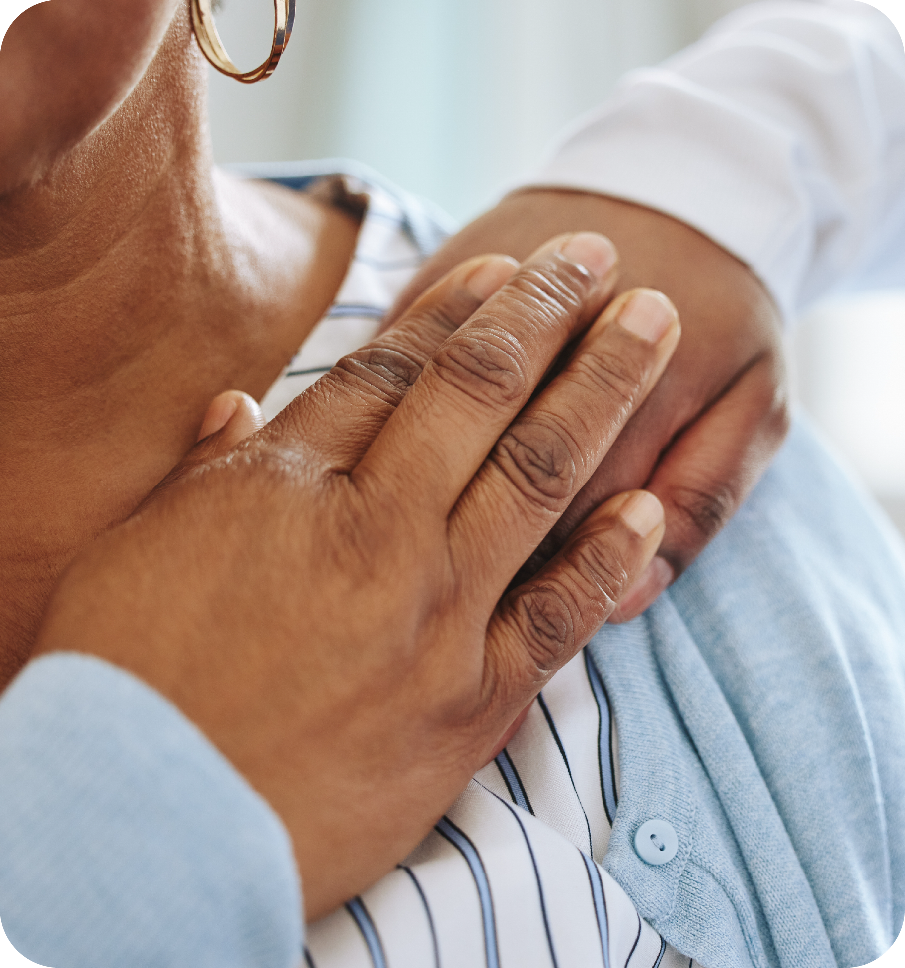 A dark woman holding a younger woman's hand on her shoulder