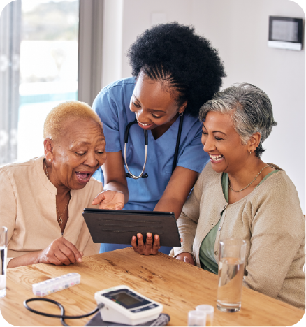 A black female nurse chatting and laughing with two colored Elderly Wmen