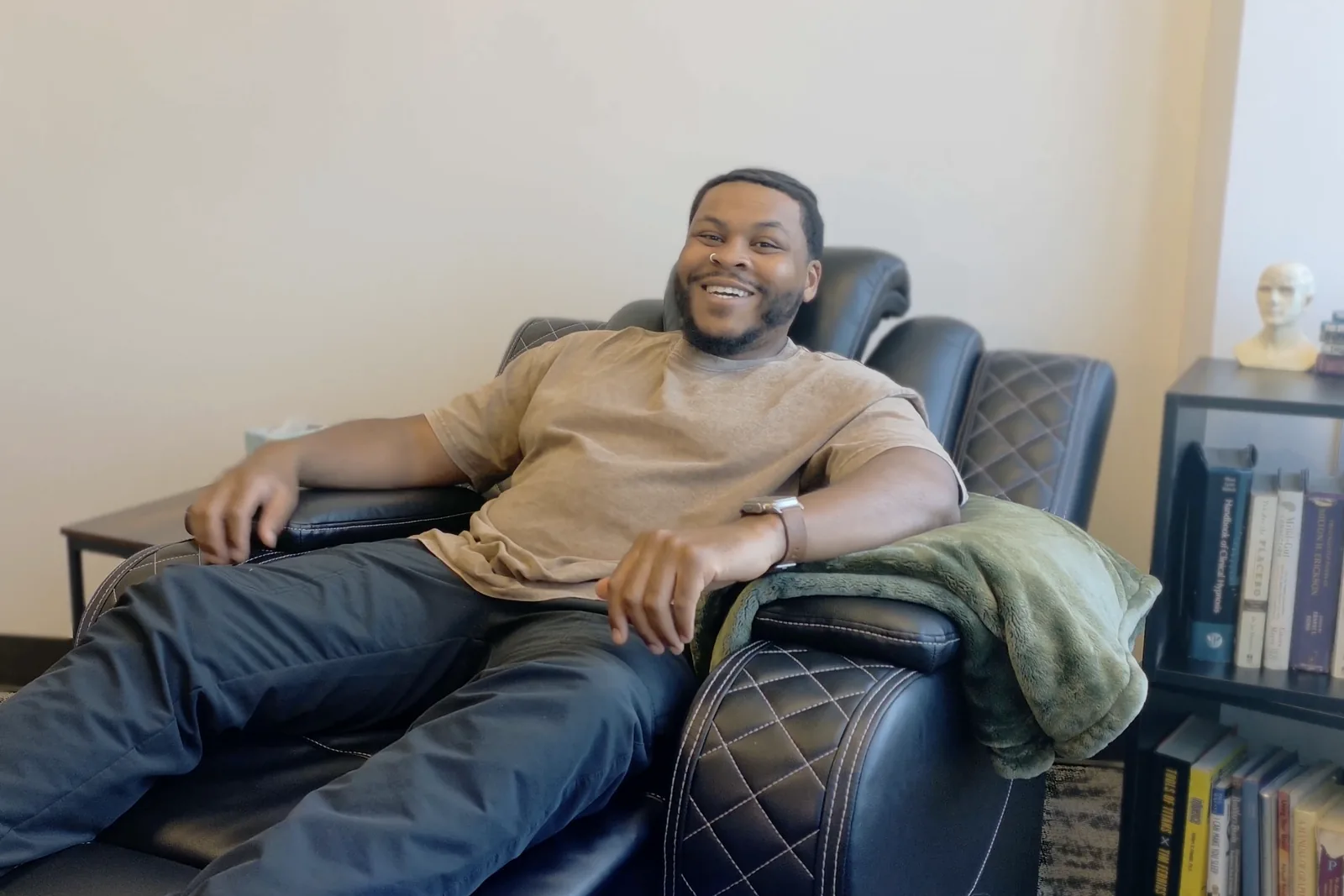 Jay Shaw, Certified Hypnotherapist, laughing as he relaxes in the black leather hypnotherapy recliner in his Oak Lawn office in Dallas
