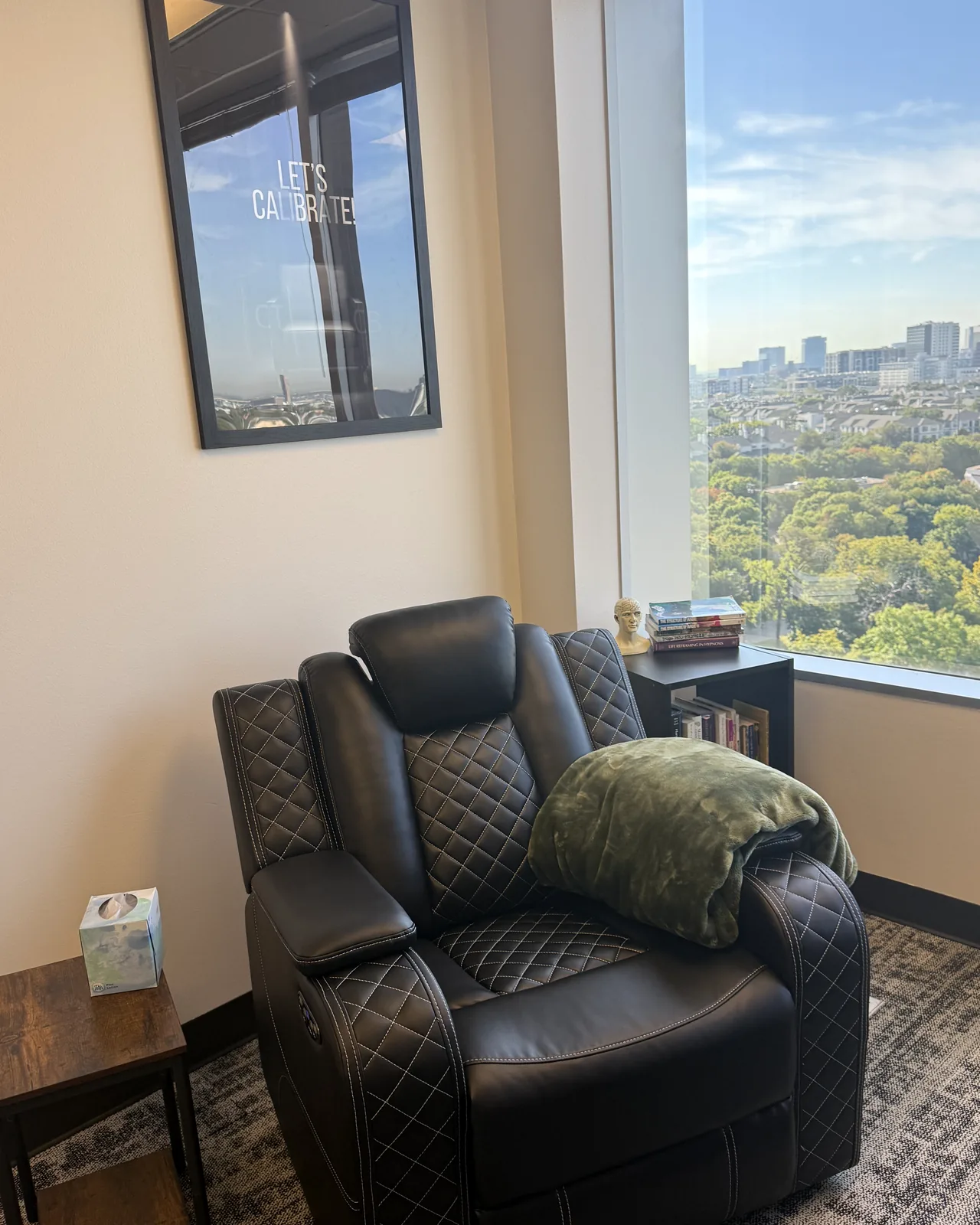 Black leather hypnotherapy recliner beside a window overlooking Dallas treetops and skyline at the Oak Lawn office