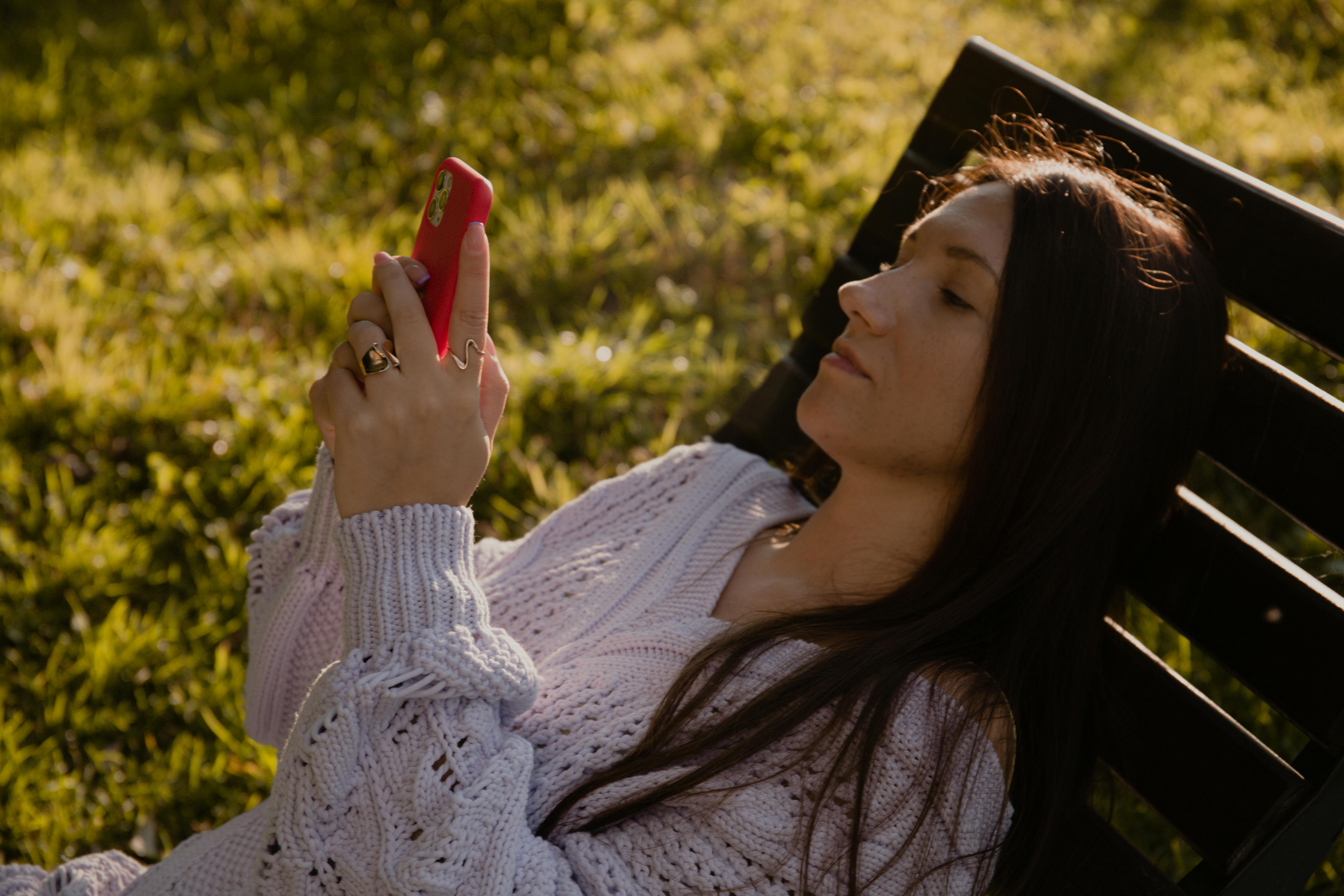 A business owner relaxed outdoors checking her phone, representing the moment a sale arrives while she is away from her desk because her marketing funnel is running in the background A business owner relaxed outdoors checking her phone, representing the moment a sale arrives while she is away from her desk because her marketing funnel is running in the background