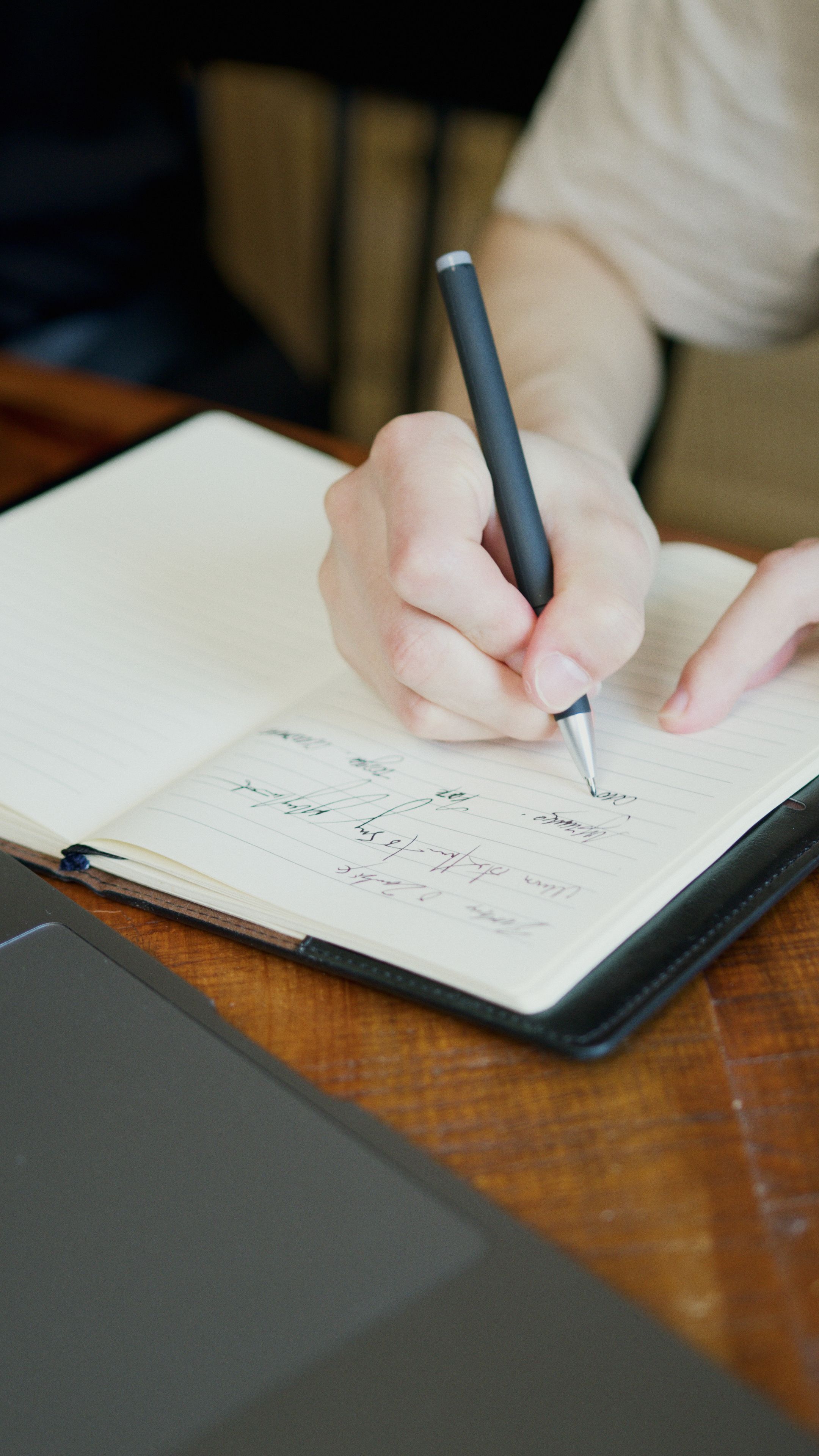 A service provider planning social media content with intention, writing in a notebook alongside a laptop with a clear structure behind each post. A service provider planning social media content with intention, writing in a notebook alongside a laptop with a clear structure behind each post.