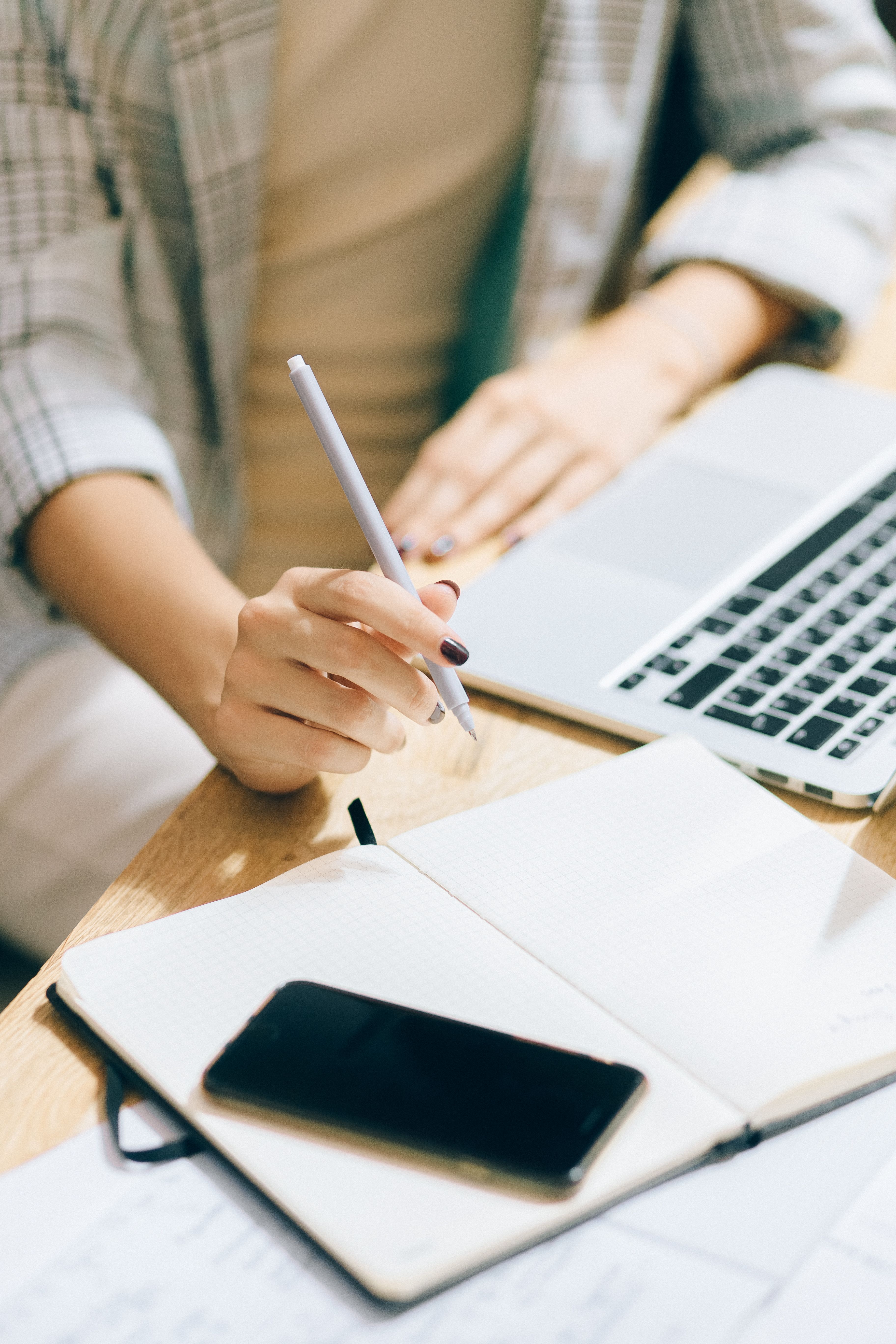 A person reviewing an open notebook alongside printed documents at a clean white desk. A person reviewing an open notebook alongside printed documents at a clean white desk.