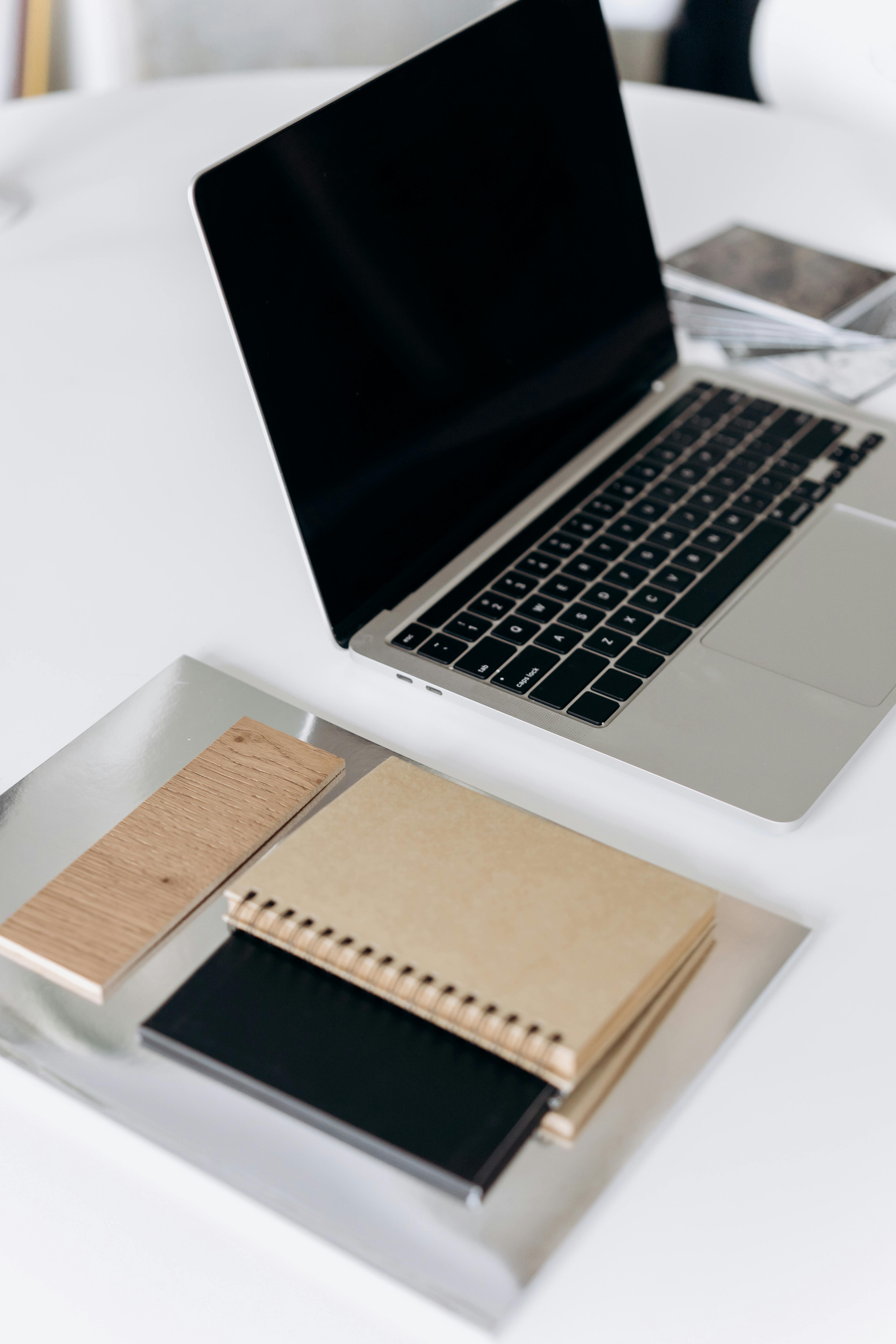 A laptop and stacked notebooks on a clean white desk representing the organised, evidence-based approach to social media content planning and review for established UK service providers. A laptop and stacked notebooks on a clean white desk representing the organised, evidence-based approach to social media content planning and review for established UK service providers.