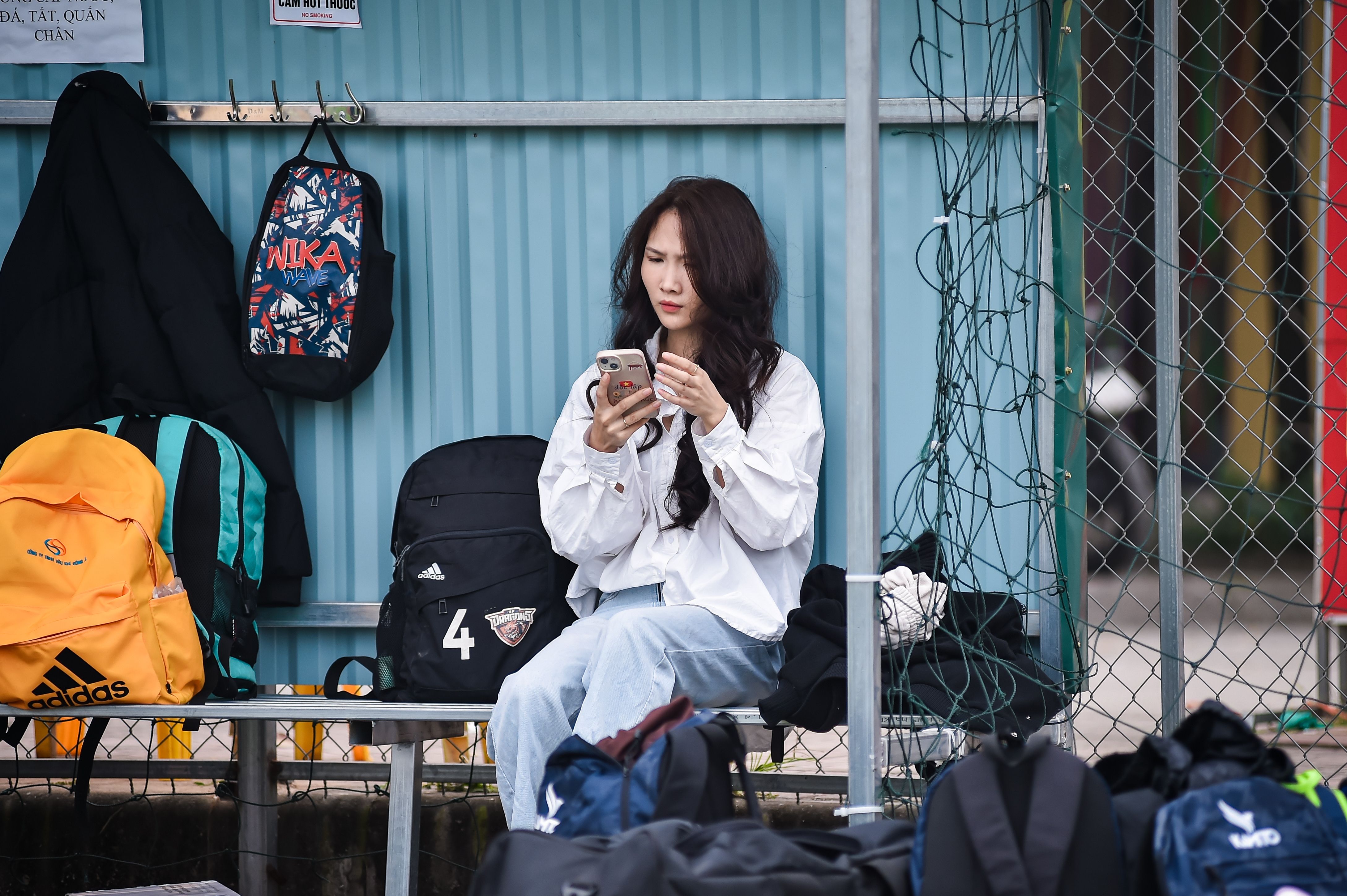 A woman on her phone at a children's sports activity representing the missed moments that accumulate when carrying too much alone in a small business. A woman on her phone at a children's sports activity representing the missed moments that accumulate when carrying too much alone in a small business.