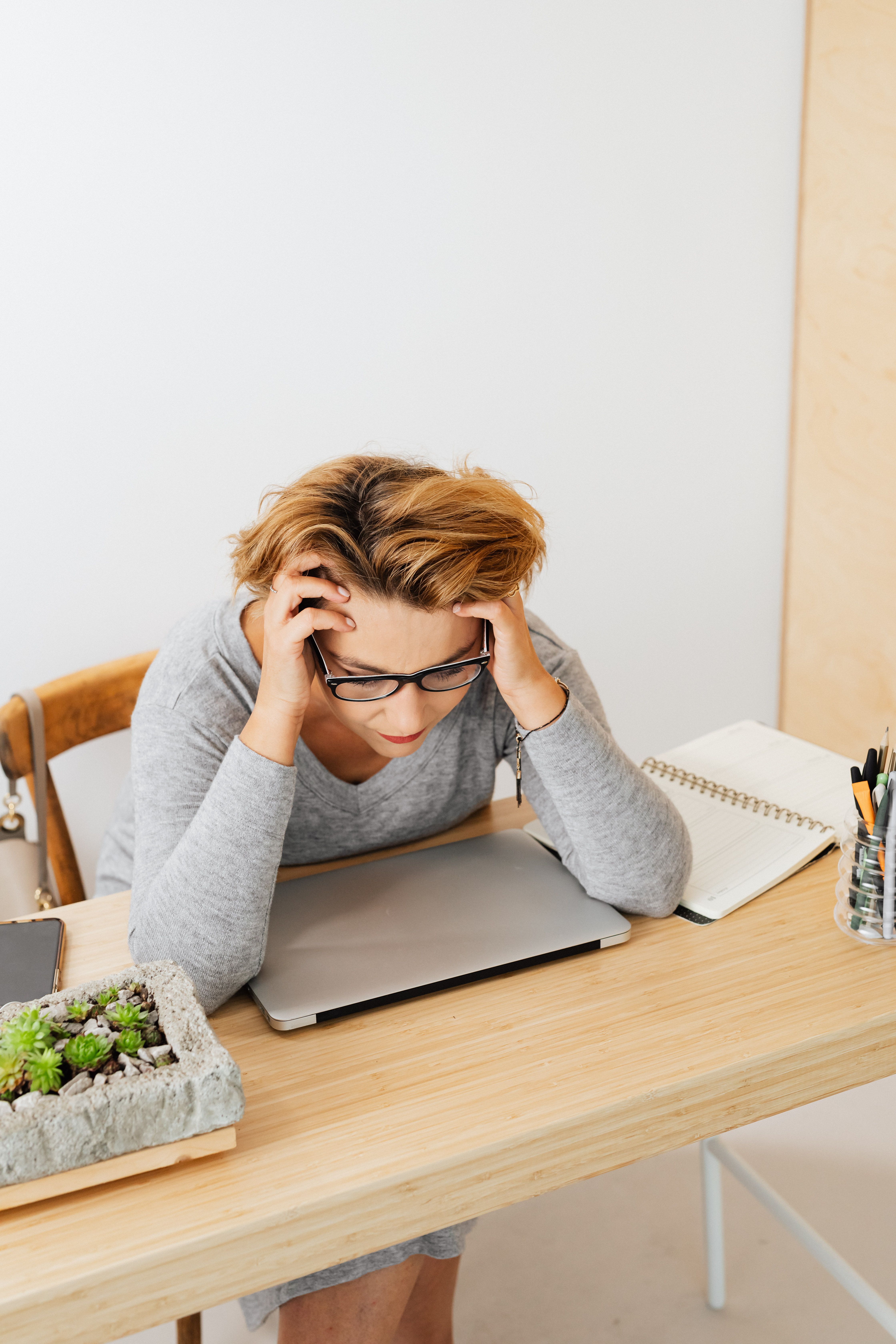 A business owner with her head in her hands over a laptop, exhausted from managing too much alone. A business owner with her head in her hands over a laptop, exhausted from managing too much alone.