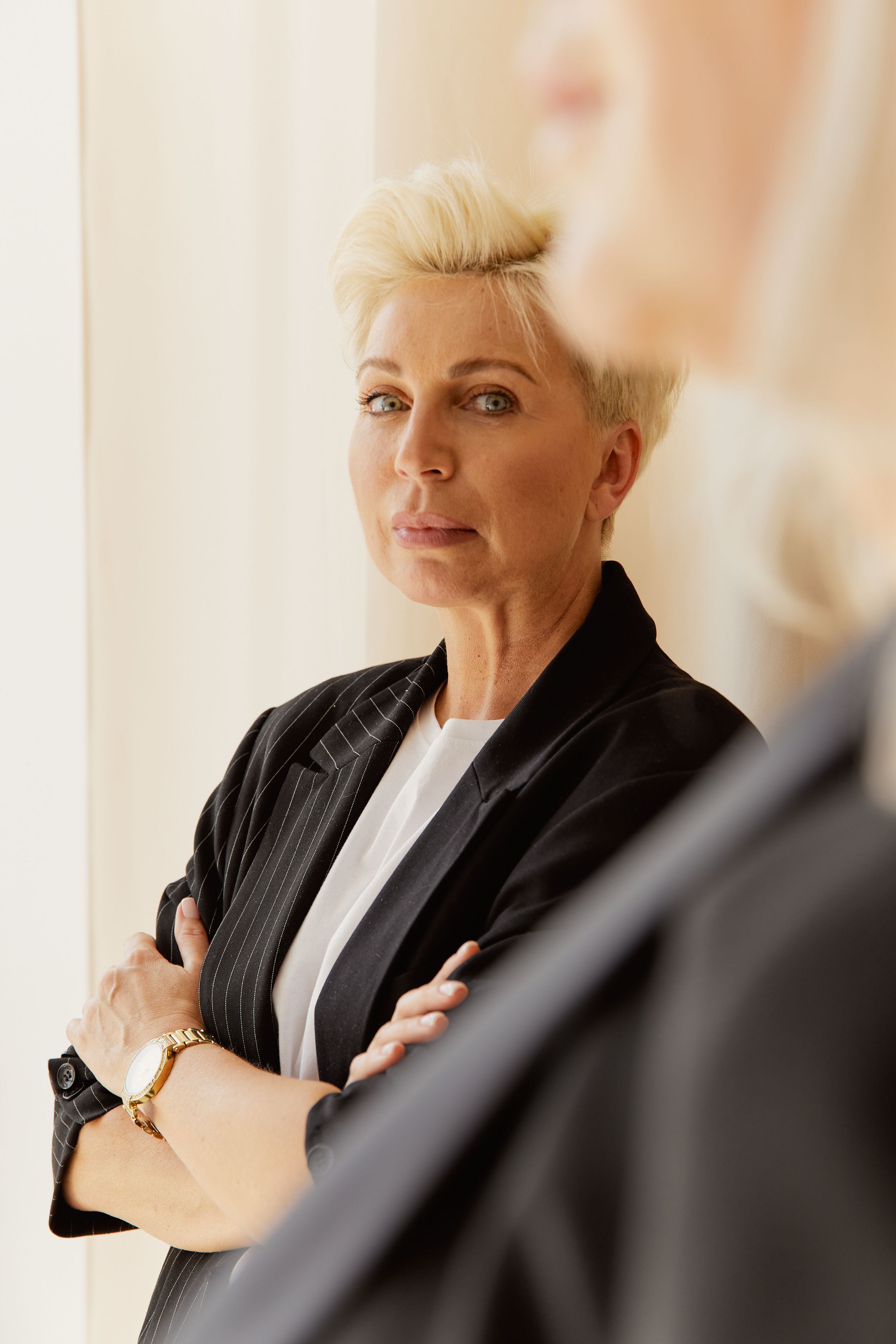 A confident business owner standing with arms folded looking forward with quiet certainty ready to make a strategic decision for her business.