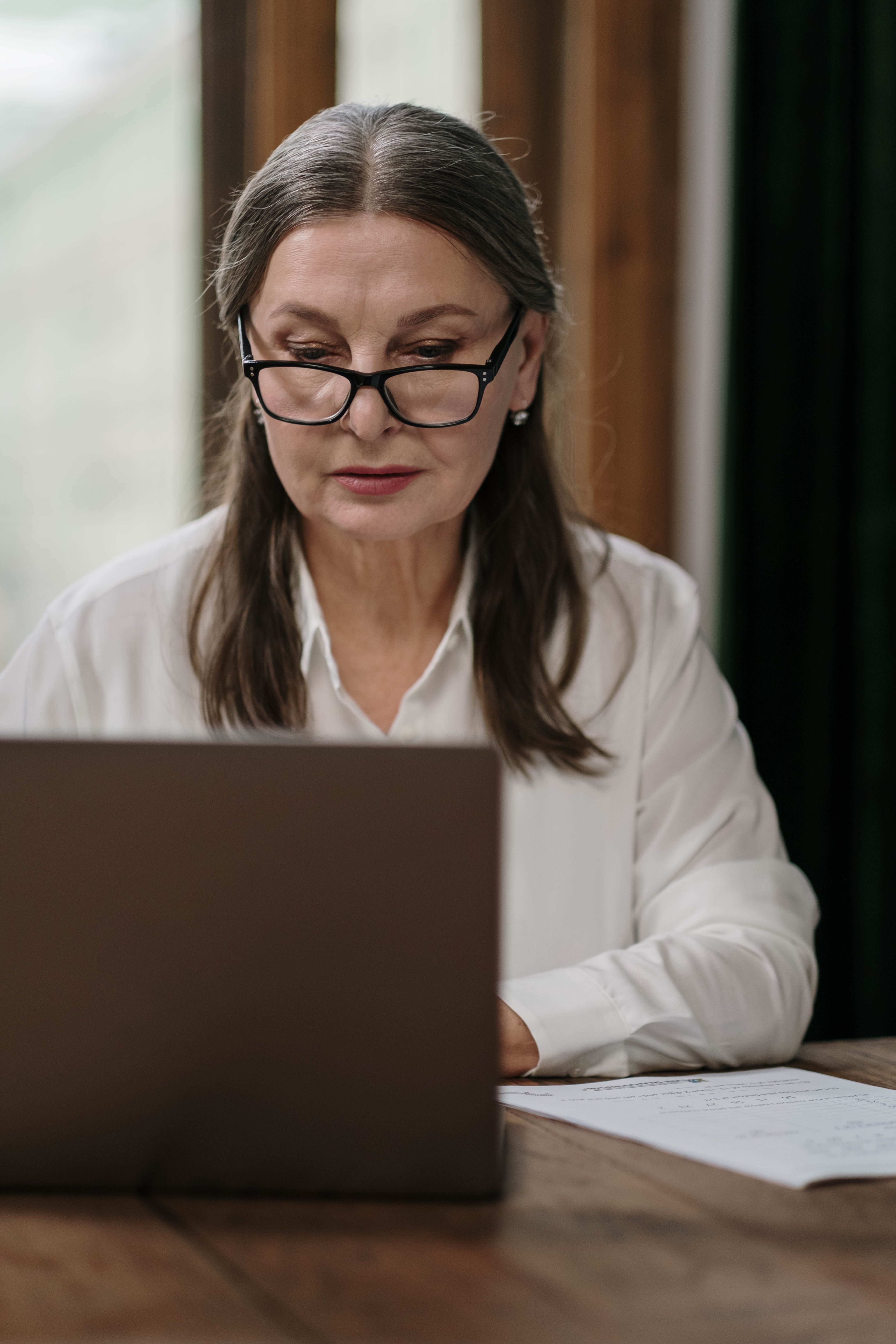 An established business owner leaning forward to read something important on her laptop screen, focused and attentive.