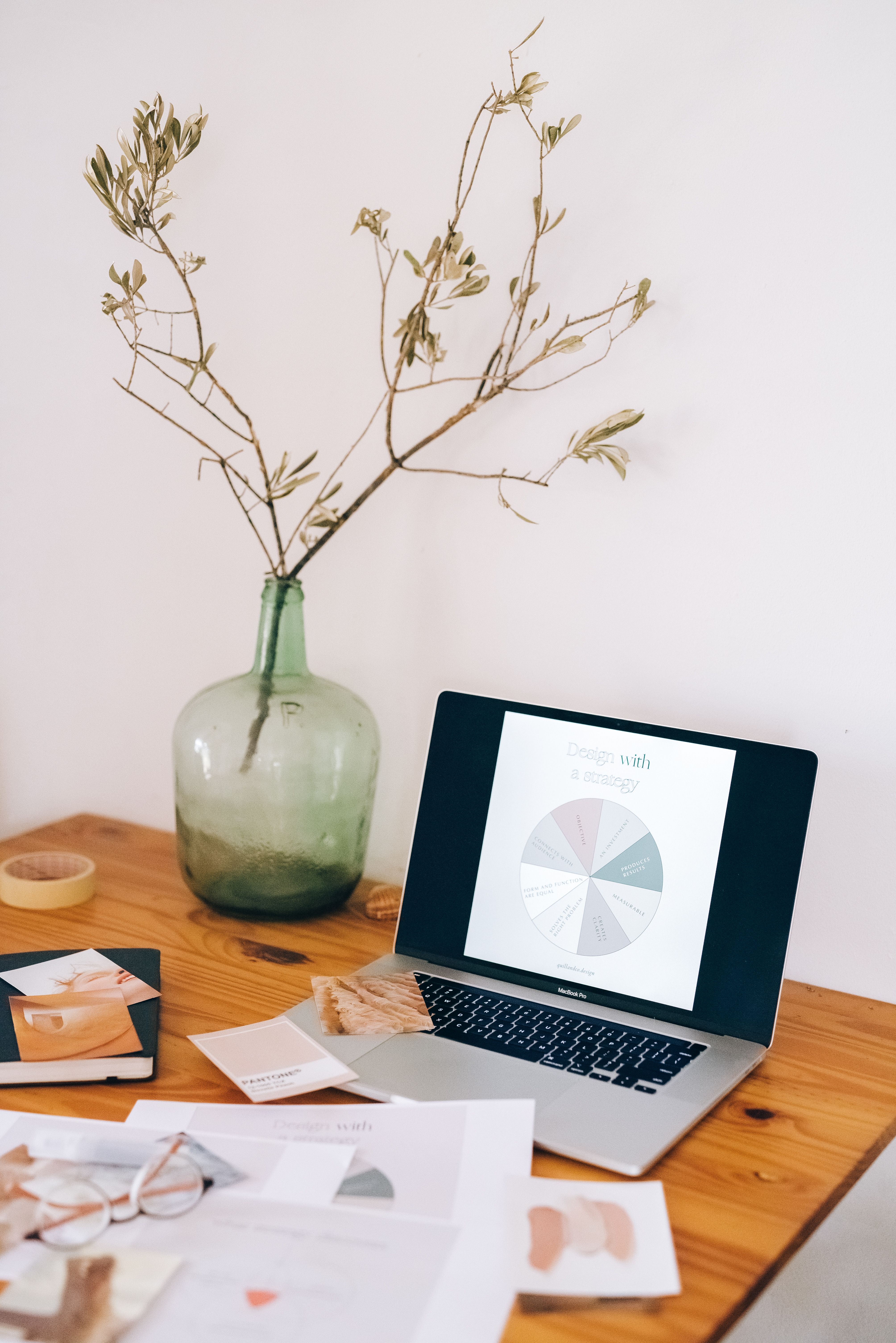 A professional workspace showing a brand strategy document on a laptop screen alongside organised design materials, representing the structured foundations that make consistent trust-building possible.