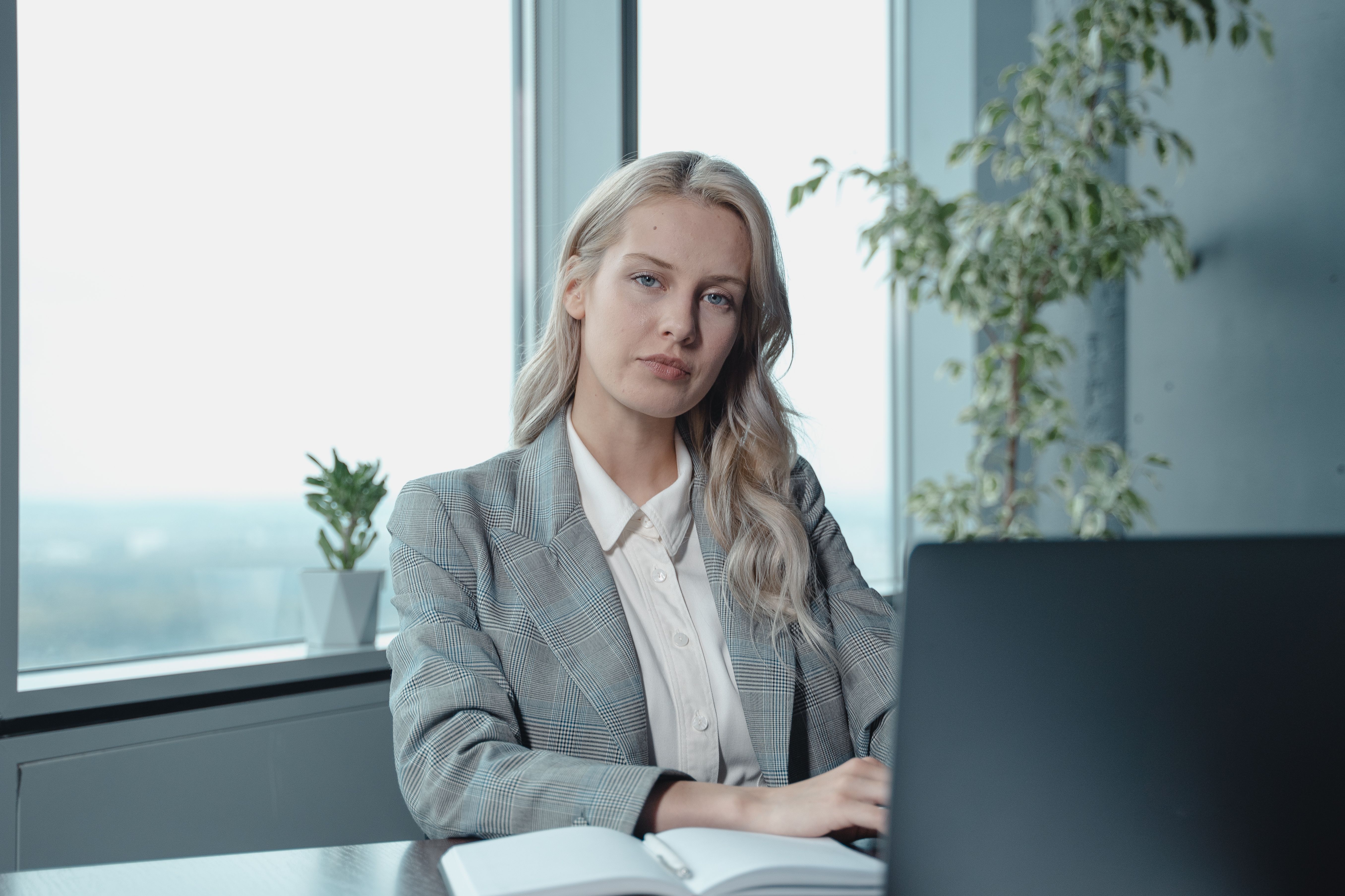 An established service provider sitting at her desk with calm confidence, representing the settled certainty of a business owner whose brand foundations are documented, clear and ready to build from.