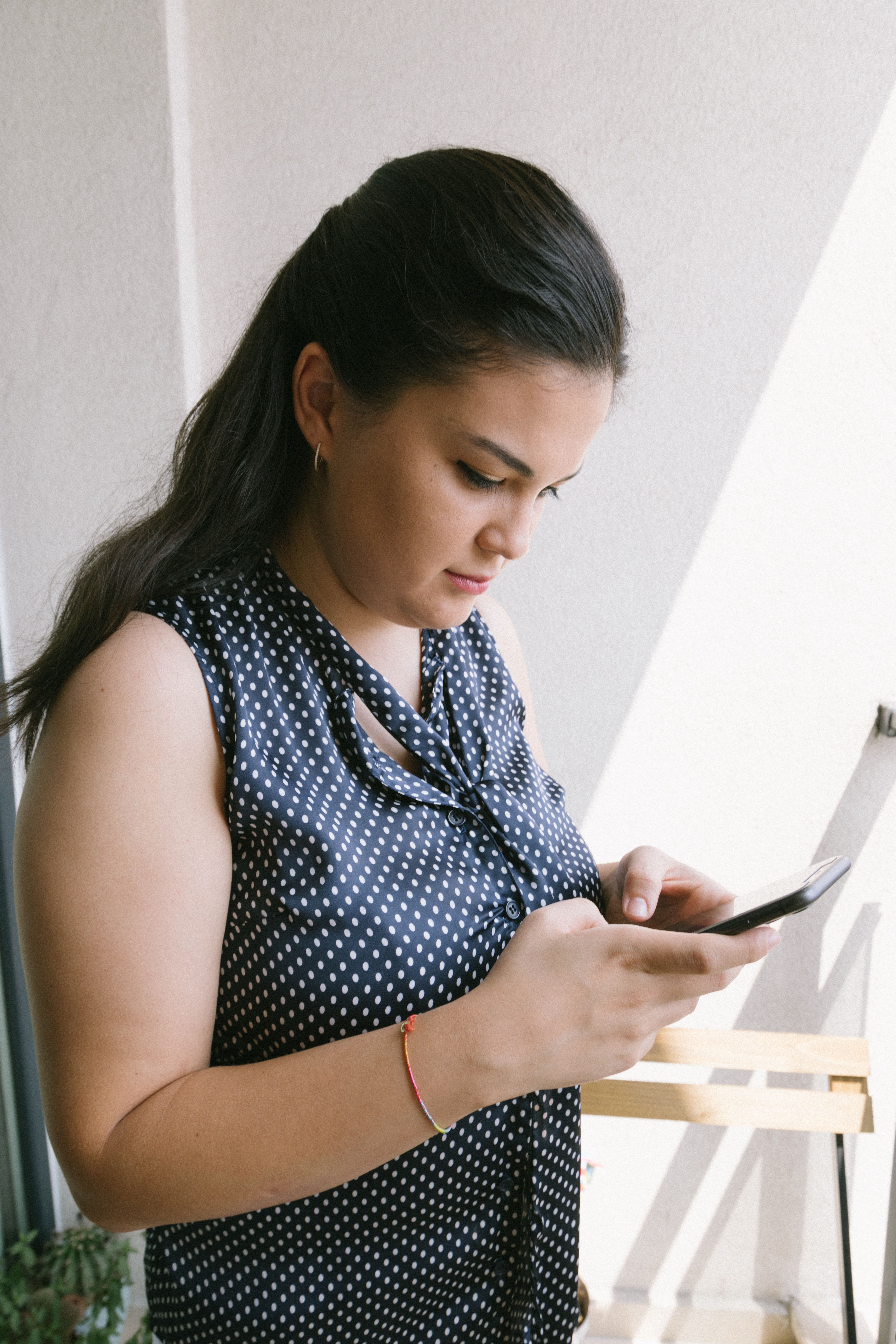 A potential client scrolling social media on her phone with a considered expression, representing the moment word of mouth sends someone to a business profile to decide whether what they find matches what they were told.