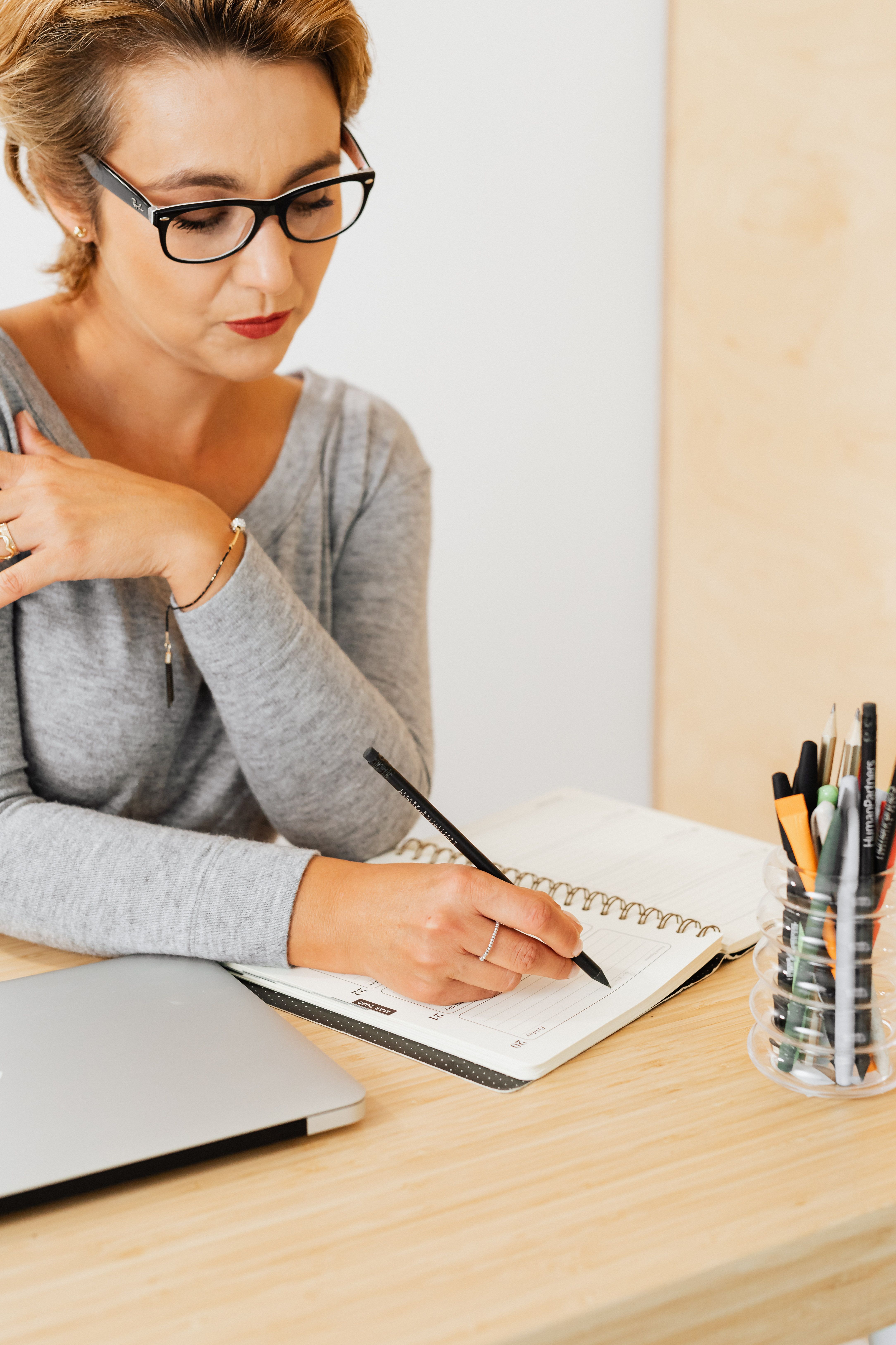 An established business owner writing in a structured planner with focused intention, representing the shift from planning week to week on instinct to having a defined commercial direction in place before the content begins.