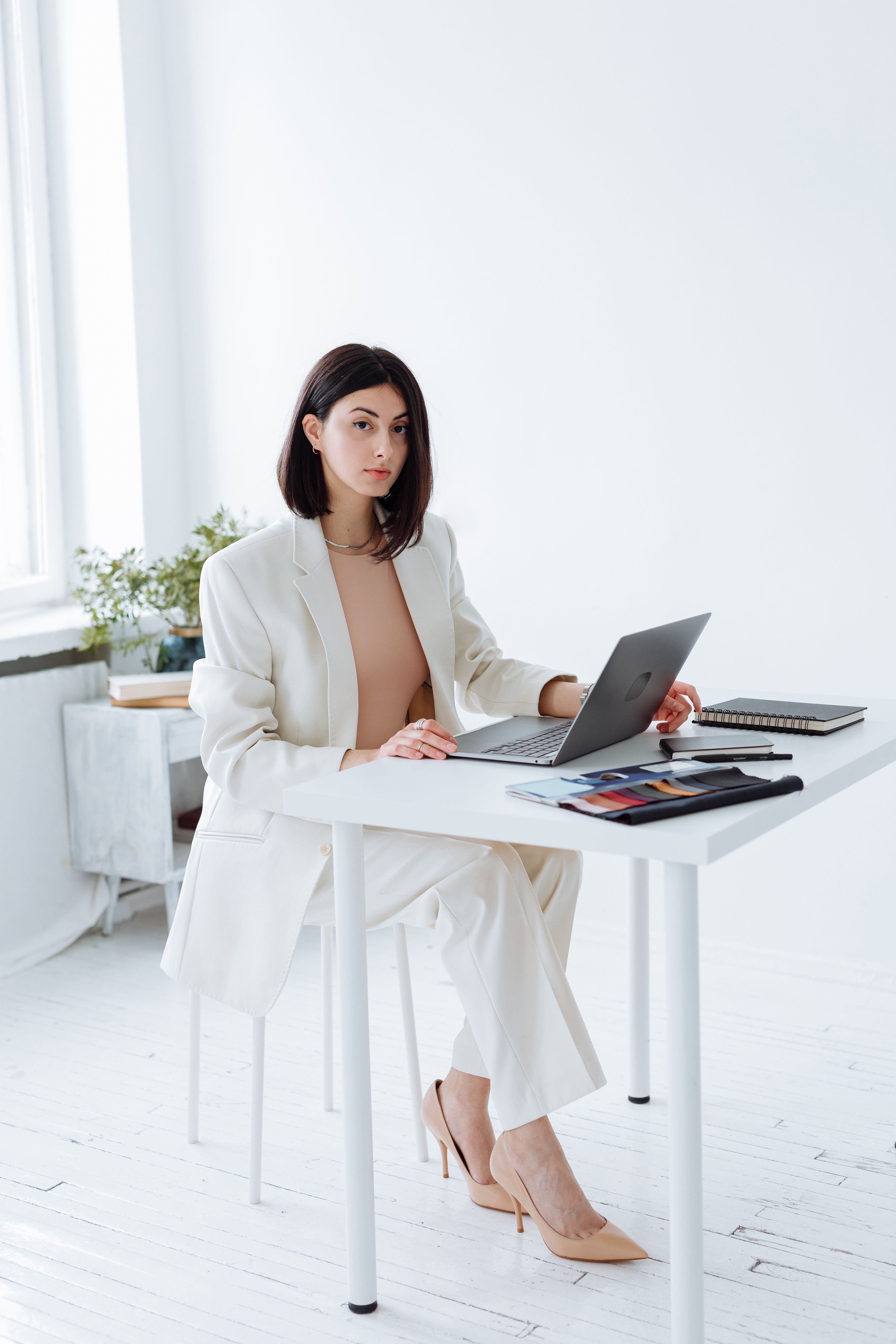 An established service provider sitting at her desk with a calm settled expression, representing the quiet forward-looking certainty of a business owner whose content has a direction and whose visibility is finally connected to her business goals.