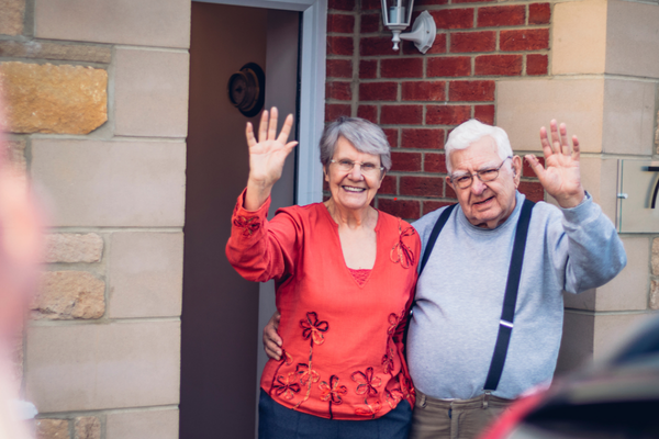 A family caregiver leaving her senior parents and being waived good bye by their parents who are aging in place safely