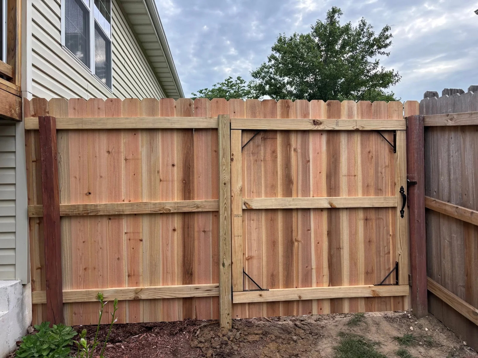 New cedar double gate and wood fence installed beside a home in Columbia, MO