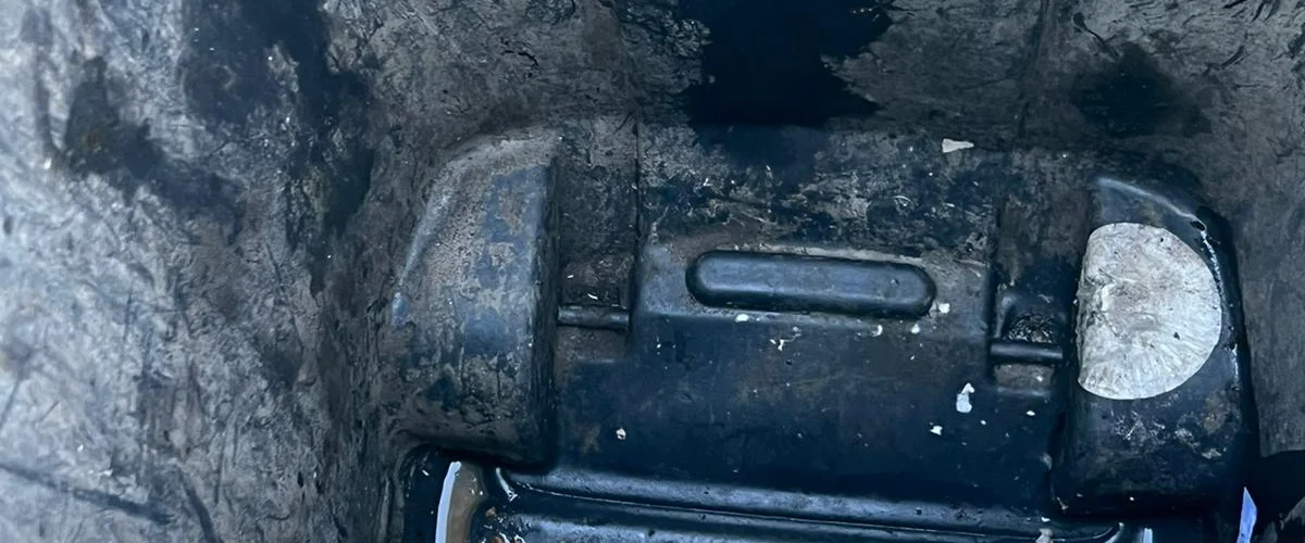 A close-up view of a dark, grimy plastic interior with water and debris, featuring an oval-shaped detail on the right. A close-up view of a dark, grimy plastic interior with water and debris, featuring an oval-shaped detail on the right.