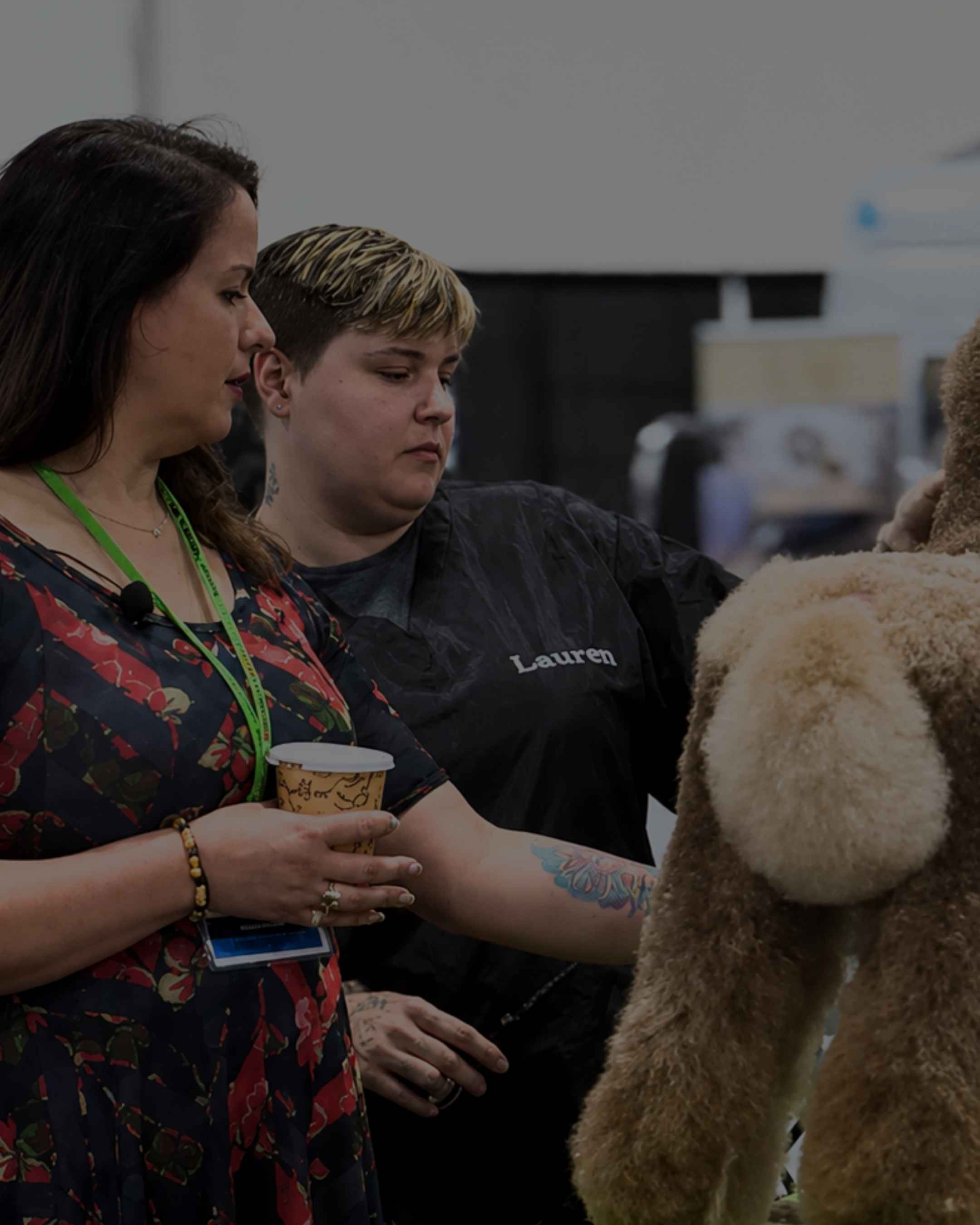 Dog grooming competition judge giving feedback to a groomer participant.