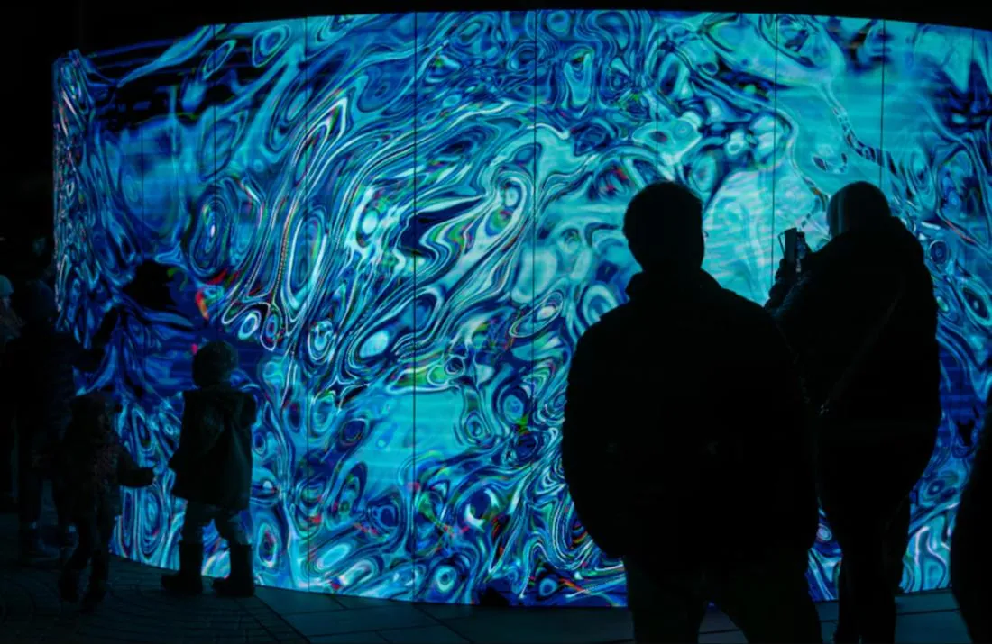 Illustrative image of visitors in front of a large responsive digital wall