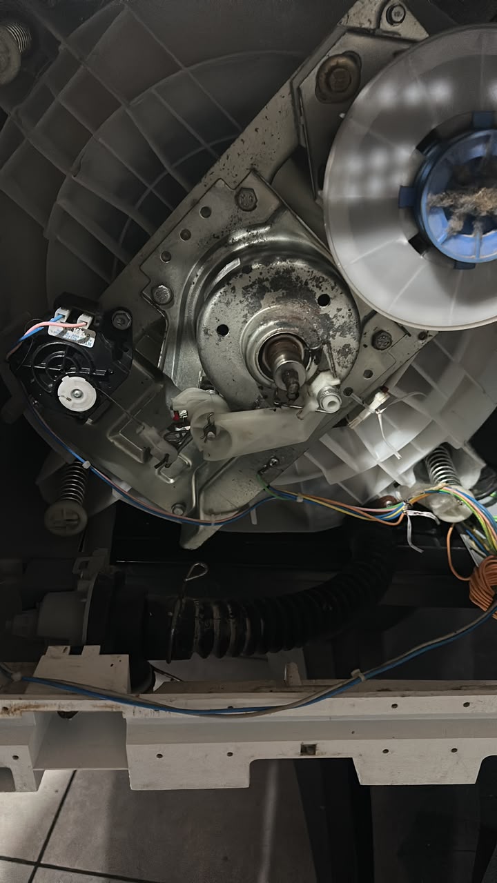 Mecanismo interno y motor de un lavarropas durante una revisión técnica