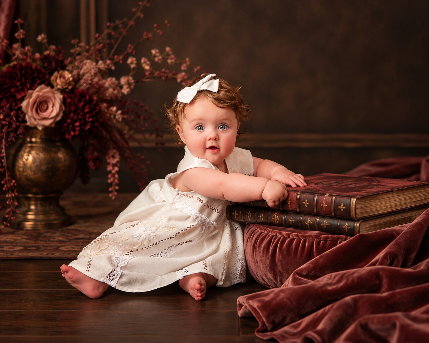 Baby in heirloom lace leaning on antique books