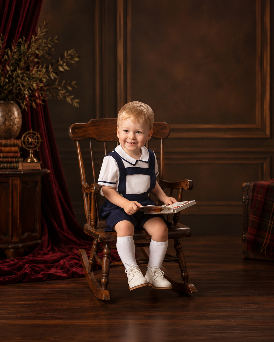 Smiling toddler in a sailor romper on a wooden rocking chair