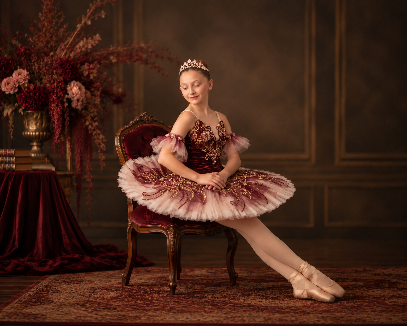 Young ballerina in an oxblood tutu seated on a velvet salon chair