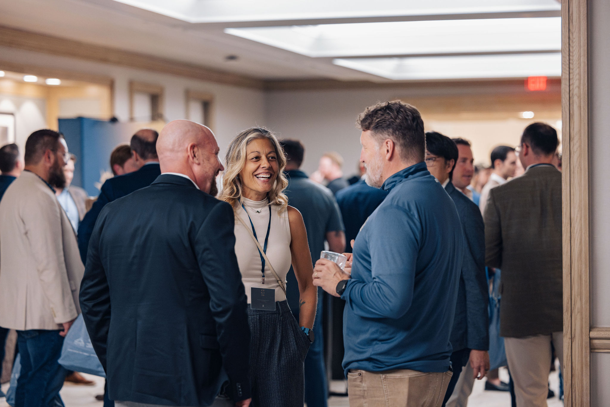 A group of people in conversation and laughing between sessions at REFINE.