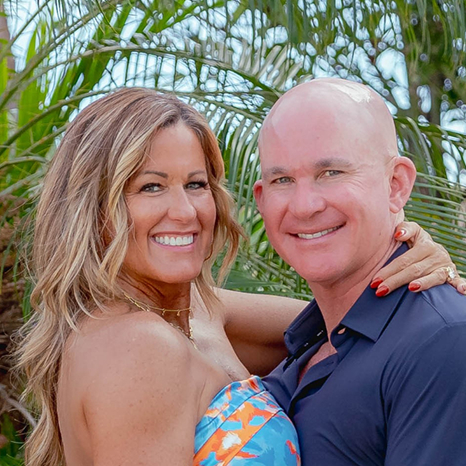 Allan and Nicole Blain smiling together in front of tropical greenery, hosts of the Life’s Hard Succeed Anyway Podcast.