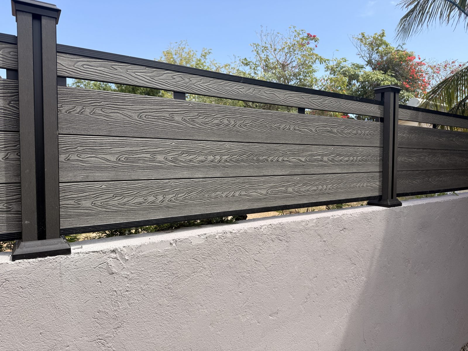 Grey WPC Fence Co. wood-grain composite fence installed on a wall in Jamaica Grey WPC Fence Co. wood-grain composite fence installed on a wall in Jamaica