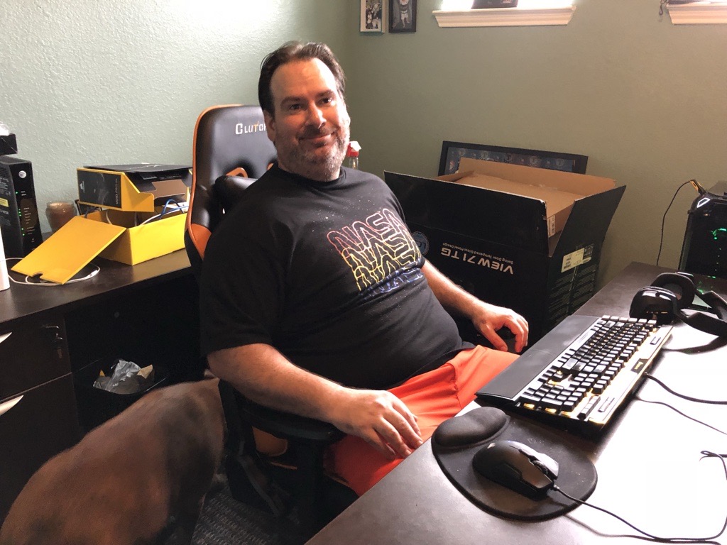 A man smiling while sitting at his desk in his home office