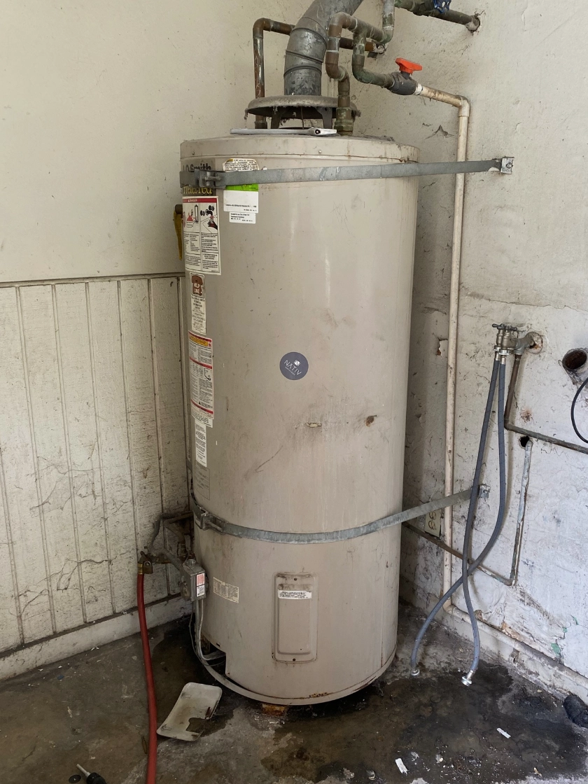 Leaking water heater with water damage on the garage floor