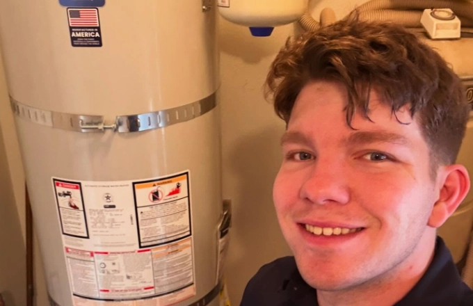 Anaheim homeowner smiling next to a new Bradford White water heater installed by Plumb Guild