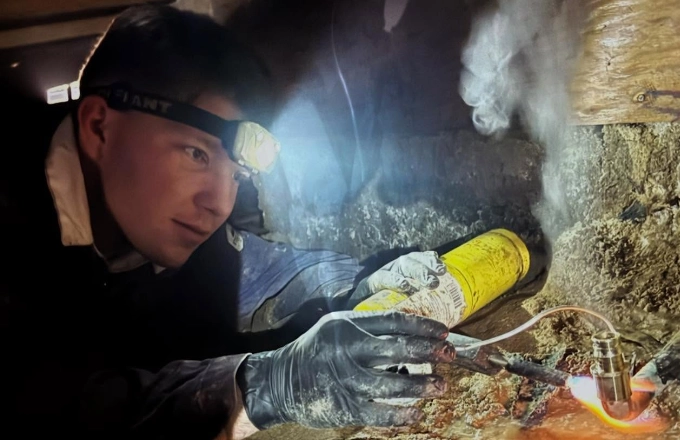 Plumb Guild plumber reviewing a water heater install with a headlamp
