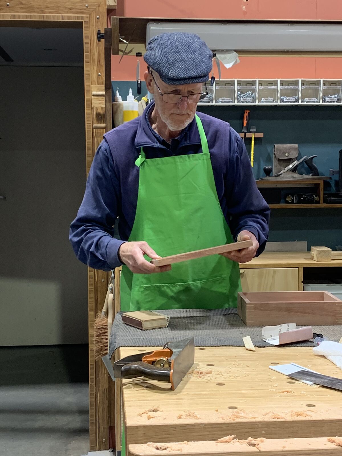 An attendee checking a piece of timber, hand plane on the bench