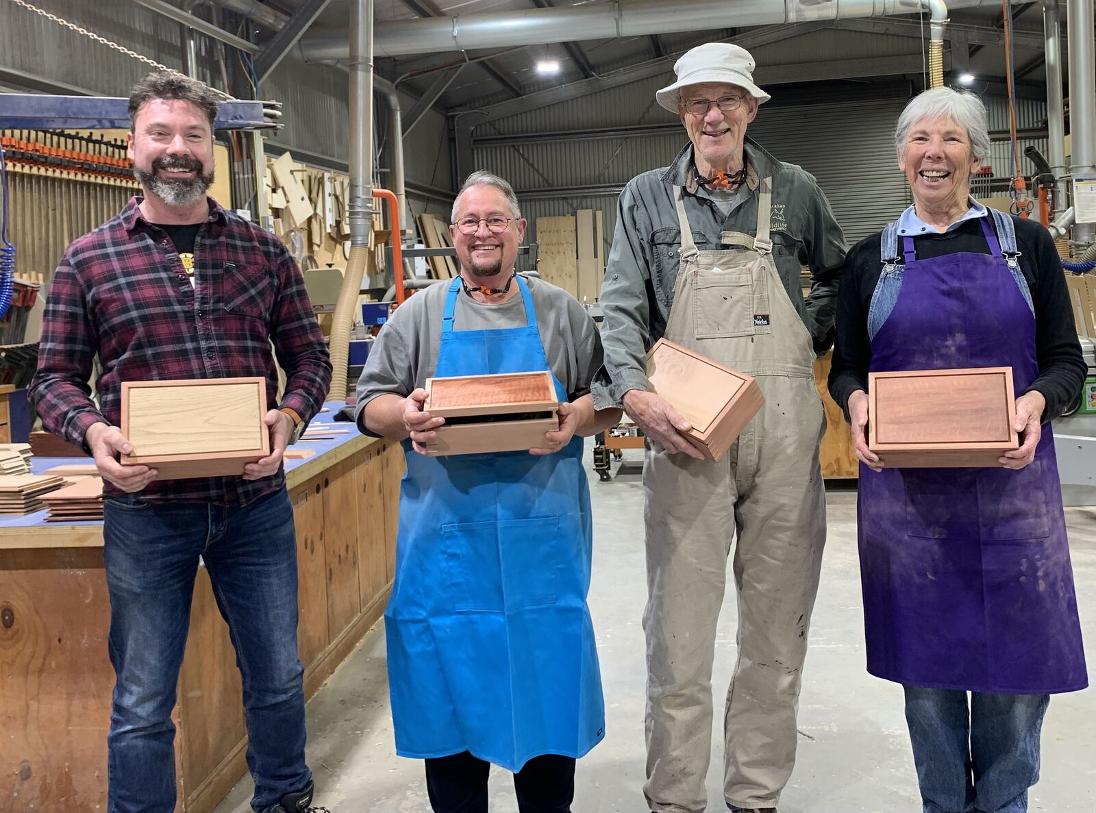 Four attendees smiling, each holding the timber box they made