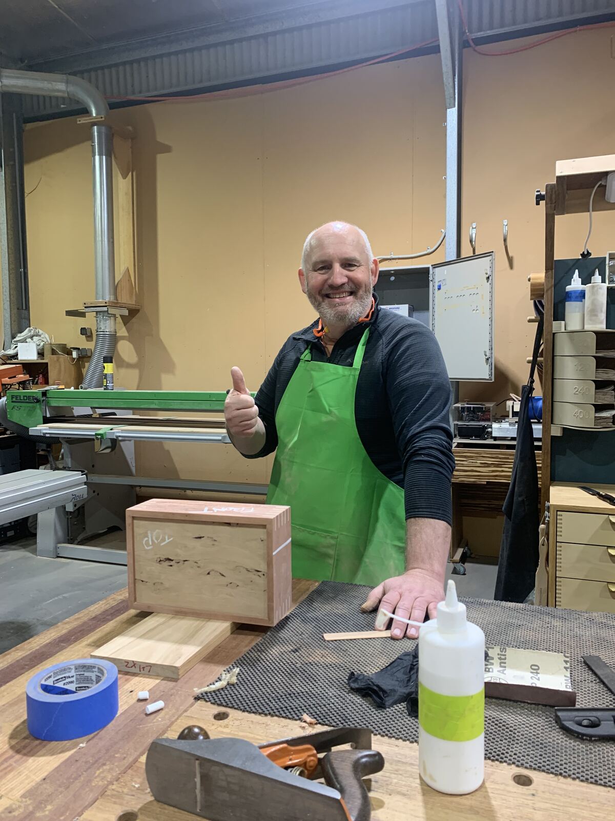 A smiling attendee giving a thumbs up beside his box