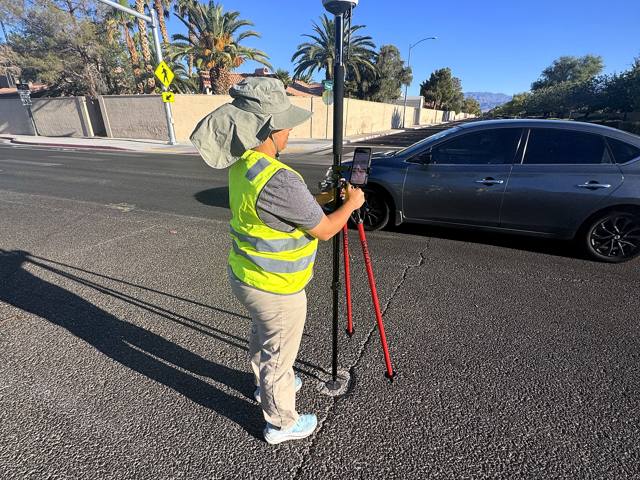 Land surveyor locating boundary property pin with survey total station equipment