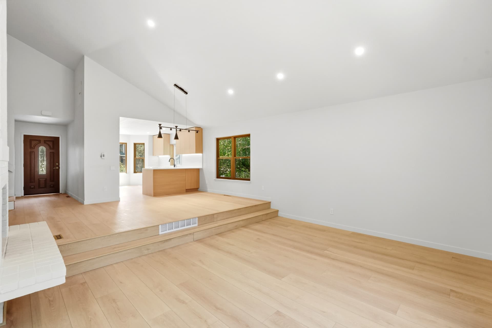 Vaulted great room with white oak floors opening onto a remodeled kitchen