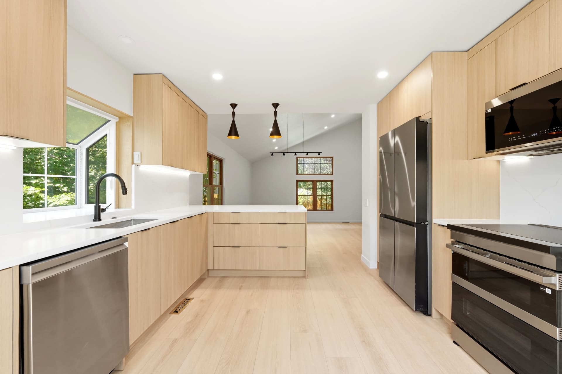 White oak flat-panel kitchen with quartz waterfall peninsula and black pendant lights