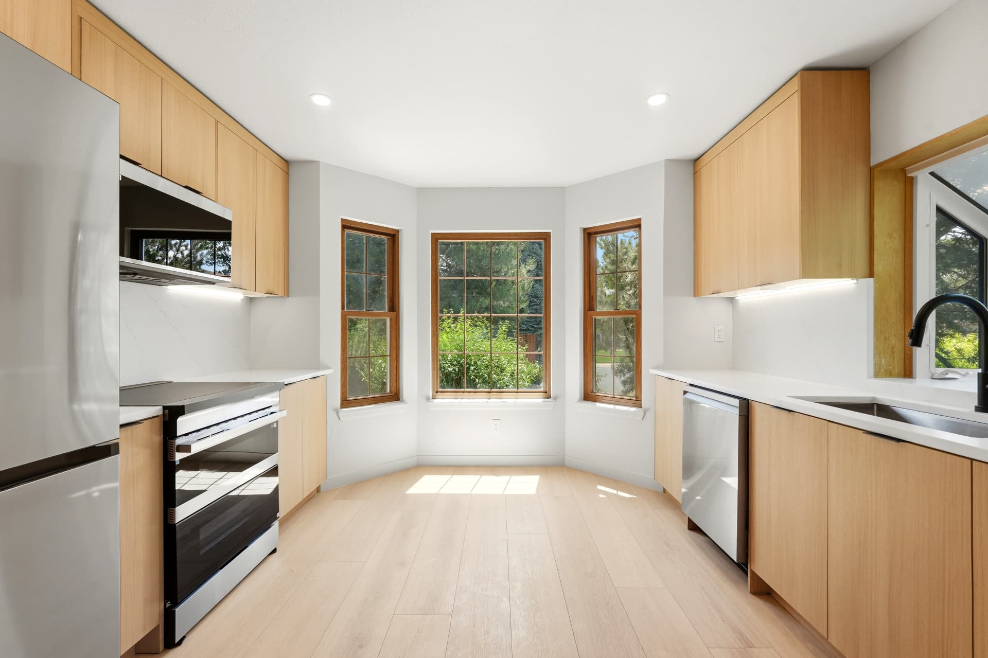 Bright kitchen remodel with bay window, light oak cabinetry and quartz countertops
