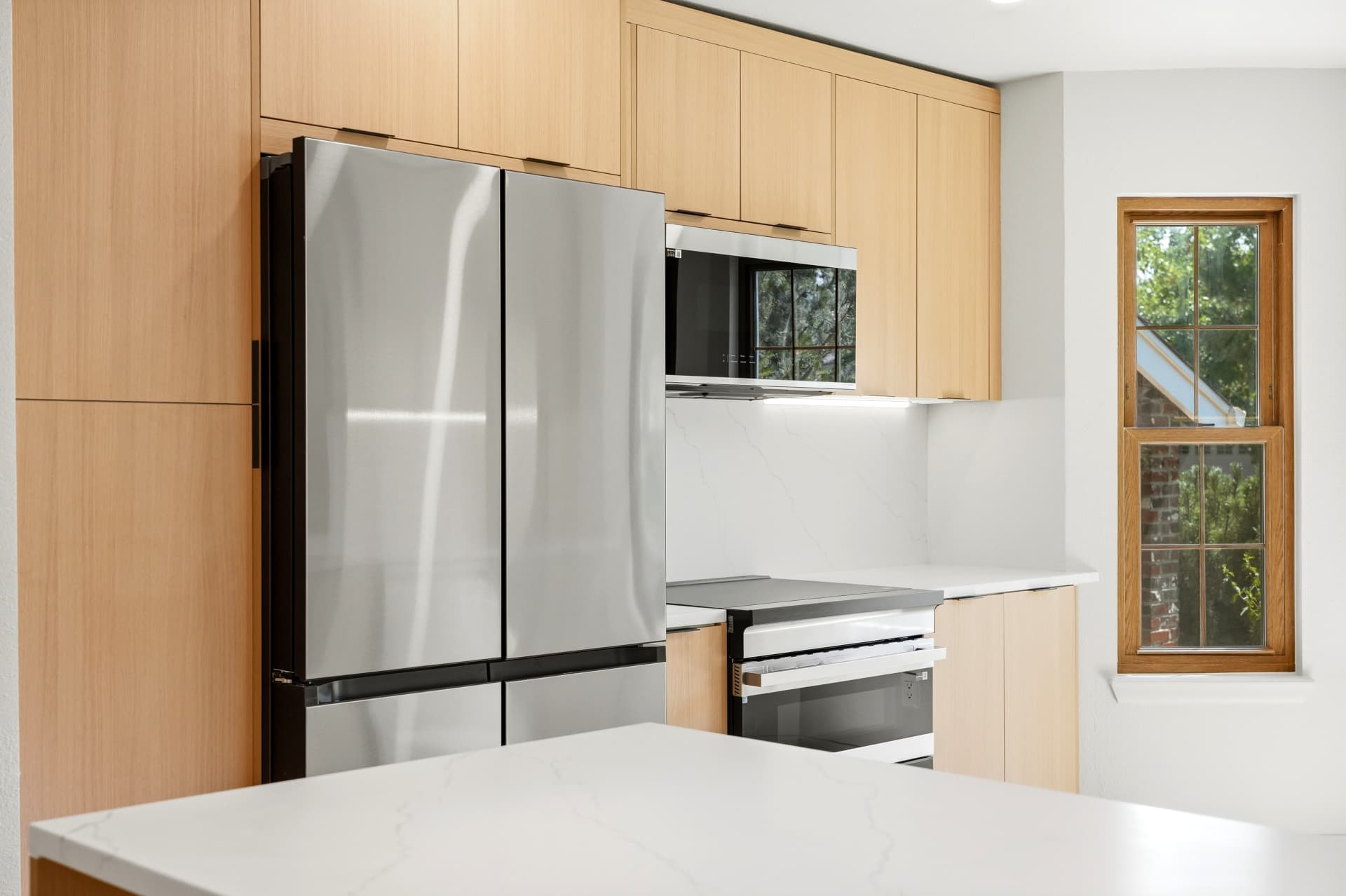 Modern kitchen with quartz waterfall island and integrated appliance wall