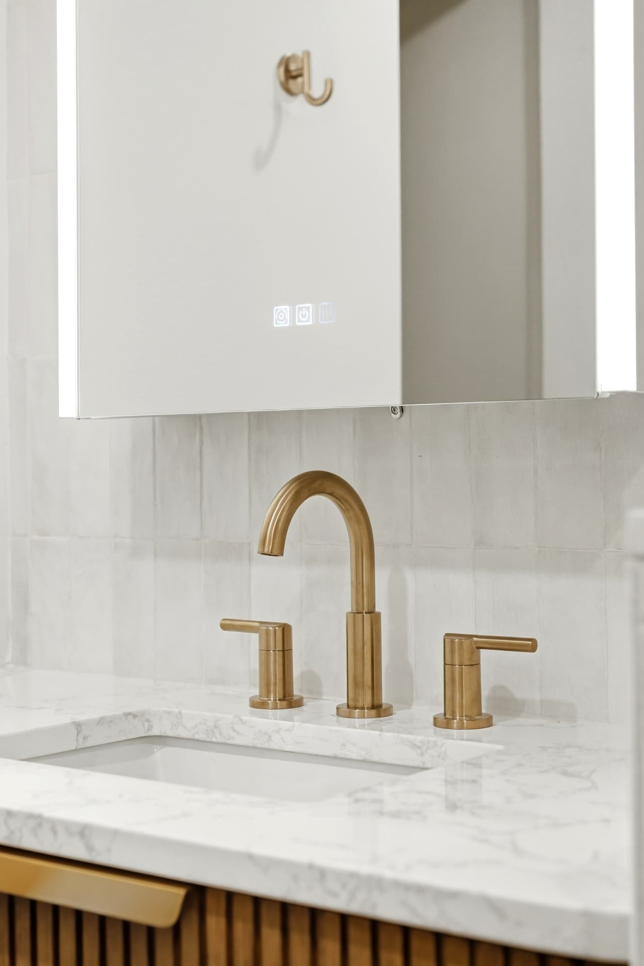 Brushed brass widespread faucet on marble vanity with zellige tile backsplash
