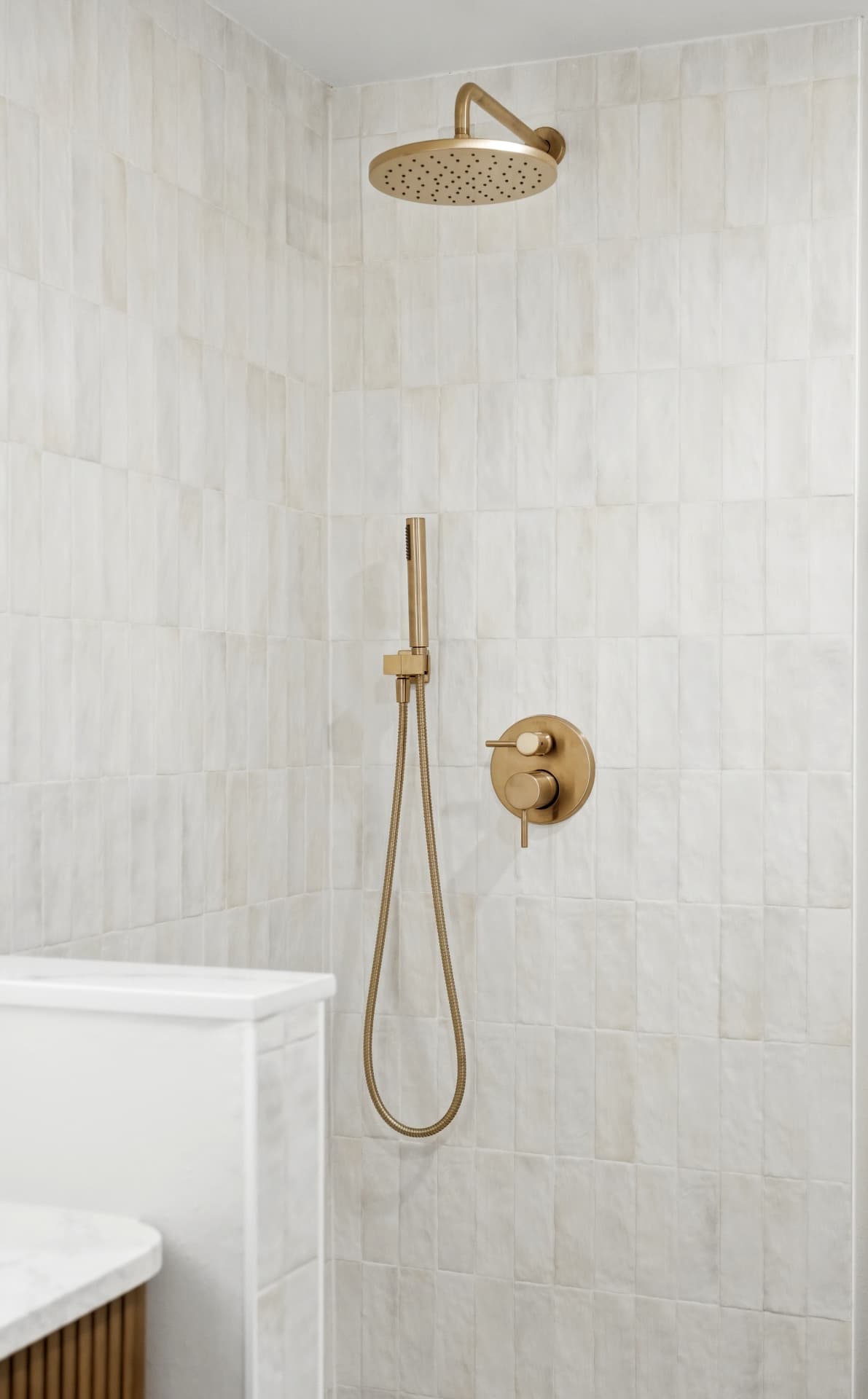 Walk-in shower with vertical zellige tile and brushed gold rainfall head and hand shower