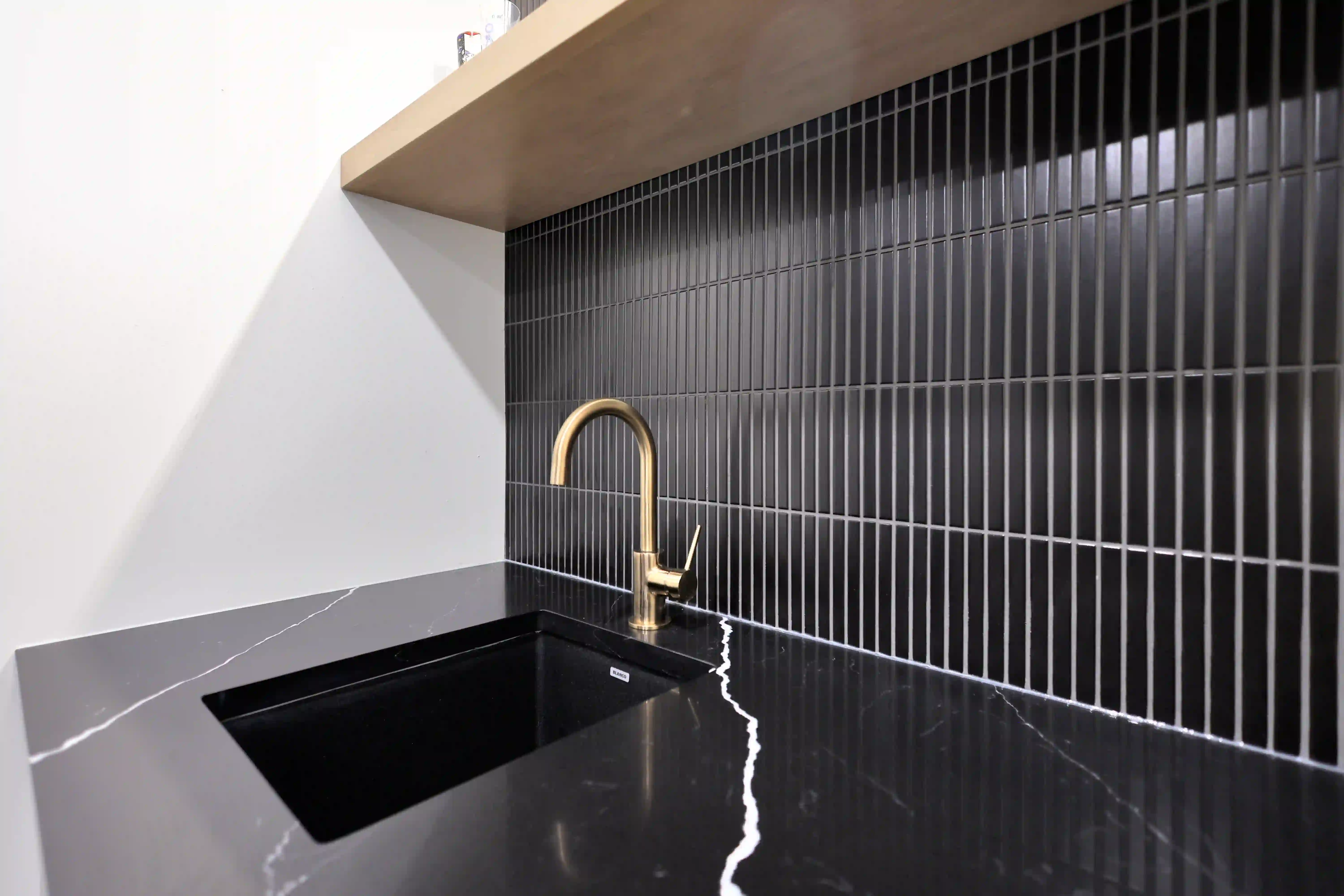 Black tile and brass faucet detail