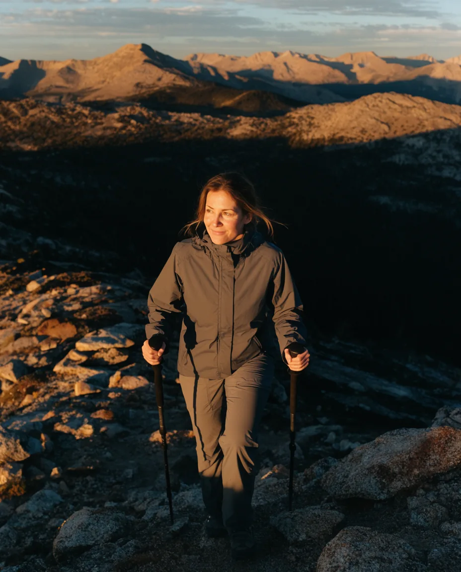 A woman hikes a mountain ridge at sunrise.