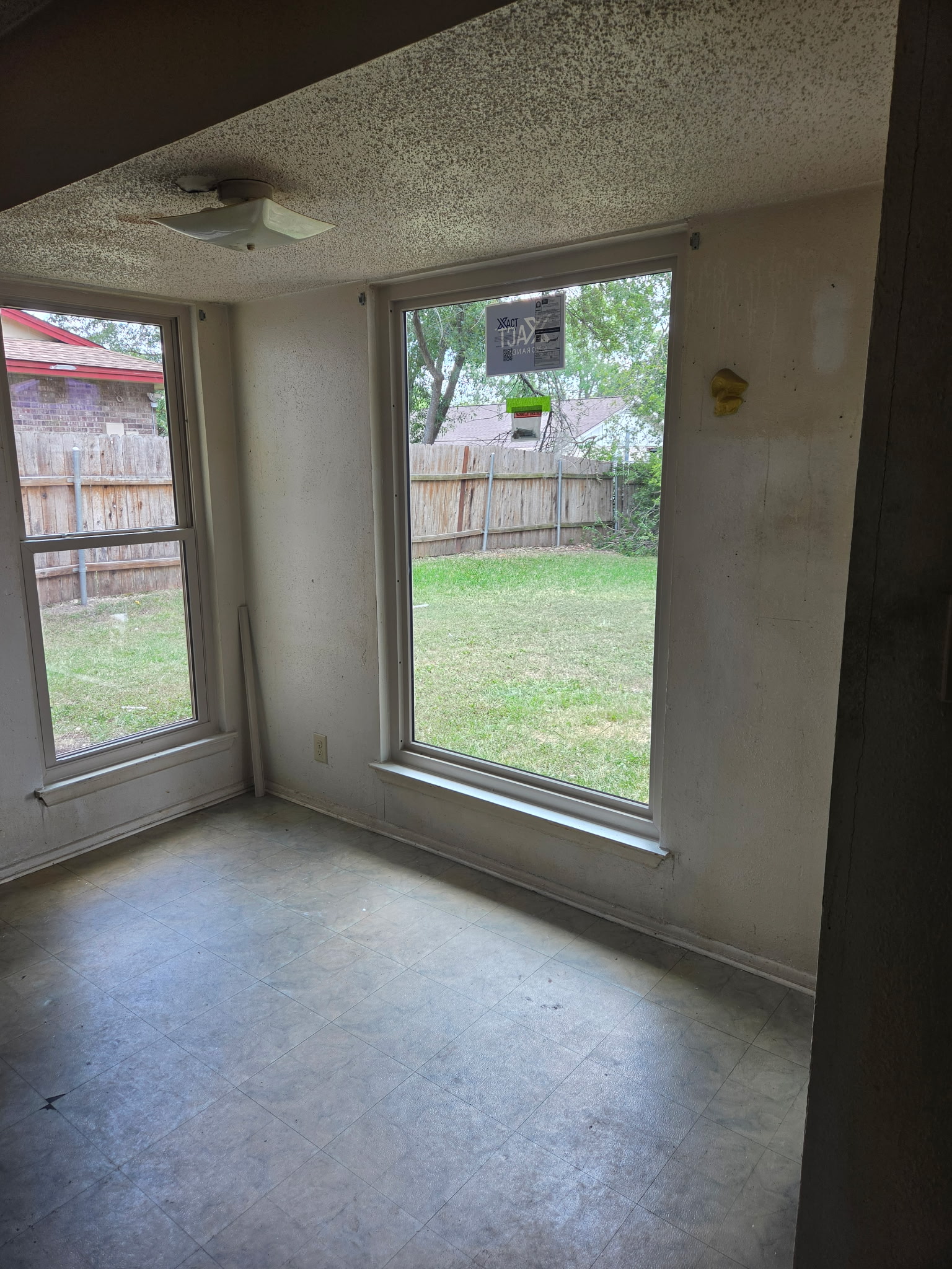 Empty room with newly installed replacement windows overlooking the backyard