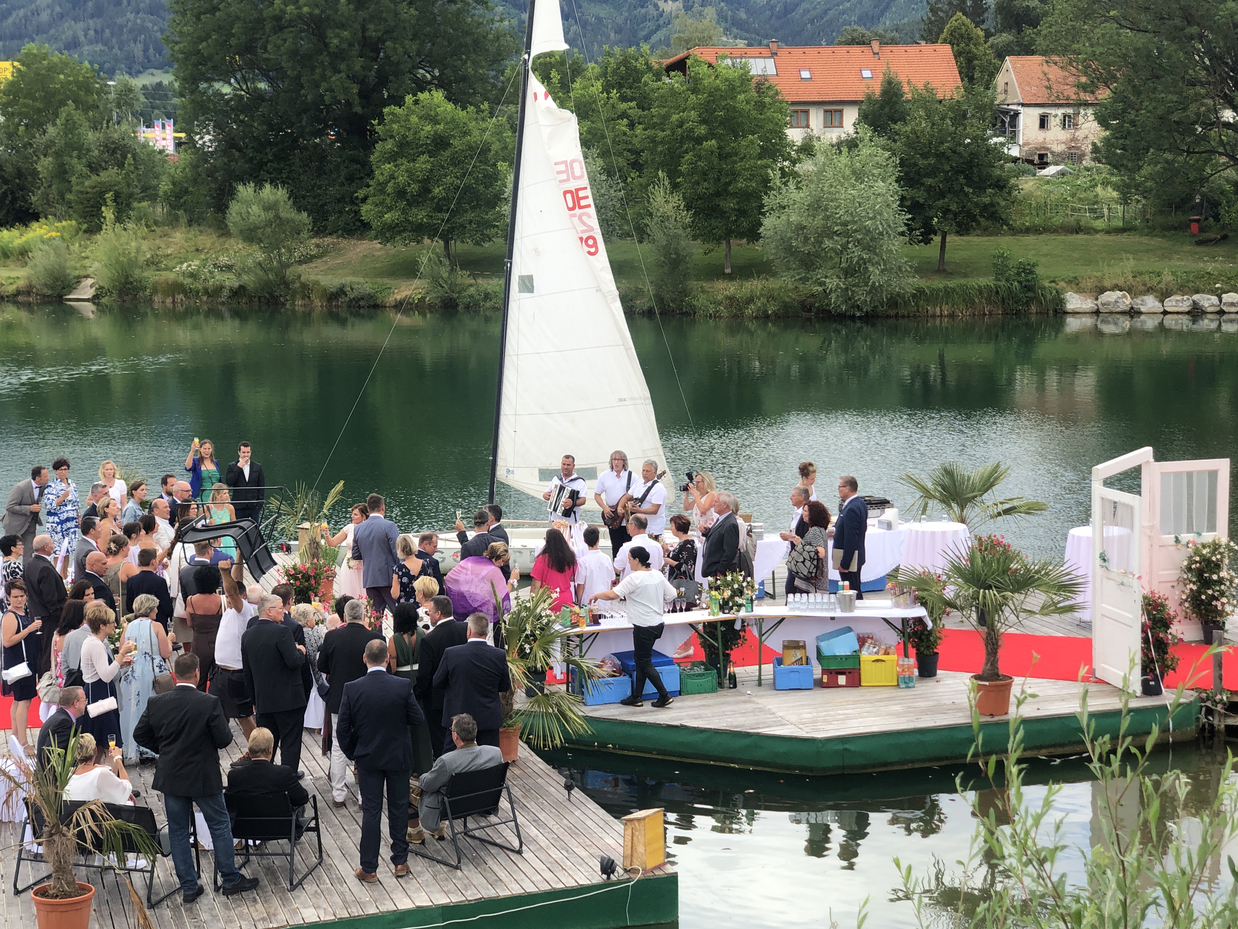 Hochzeitszeremonie mit Gästen auf einem Steg am See mit Segelboot bei Flasch City hochzeitslocation near krieglach