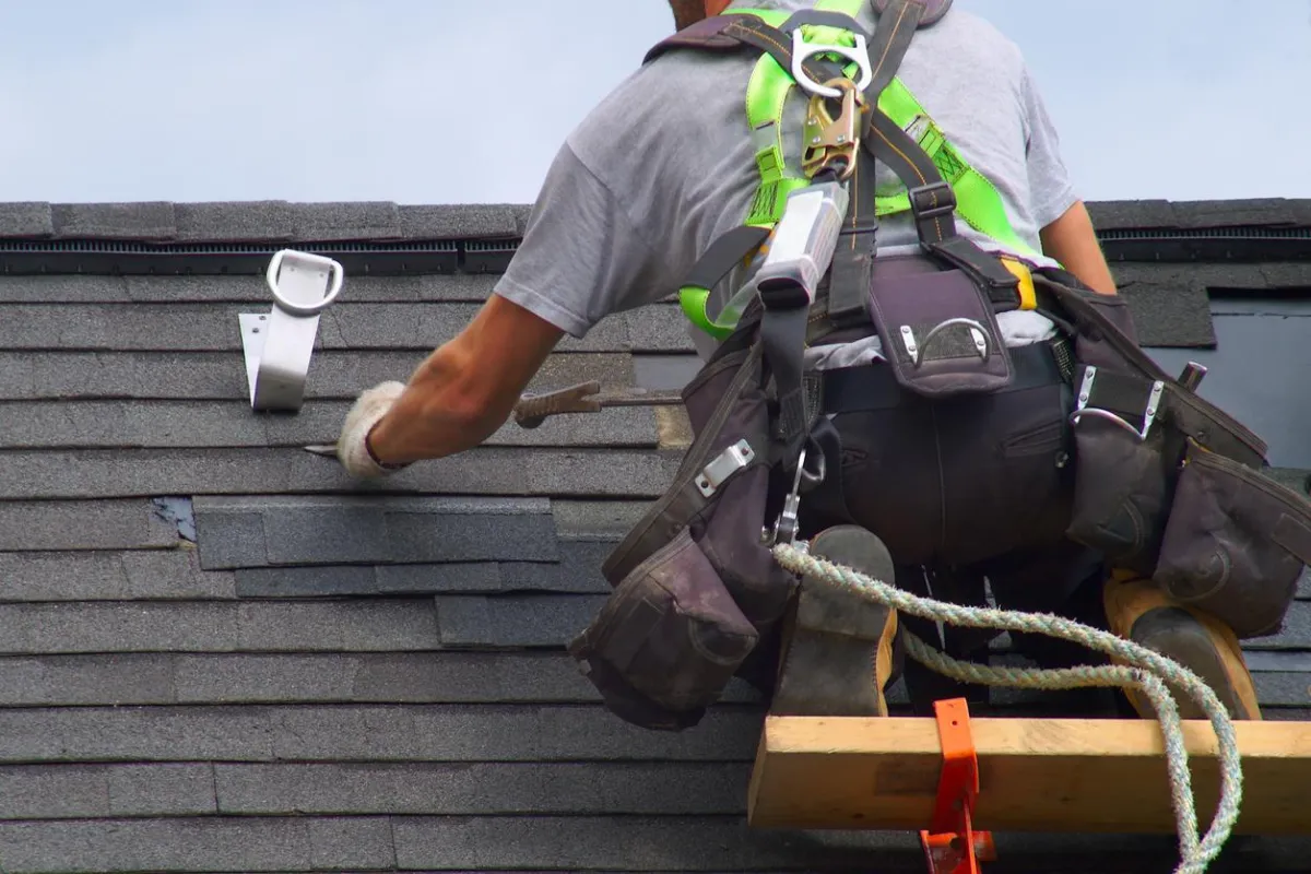 Roof repair and maintenance project showcasing a gray house with a completed, durable asphalt roof