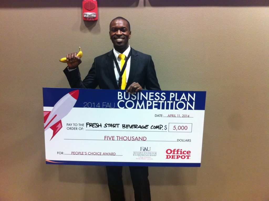 Michael Baptiste holding the $5,000 People's Choice Award check at the 2014 FAU Business Plan Competition, made out to Fresh Start Beverage Company