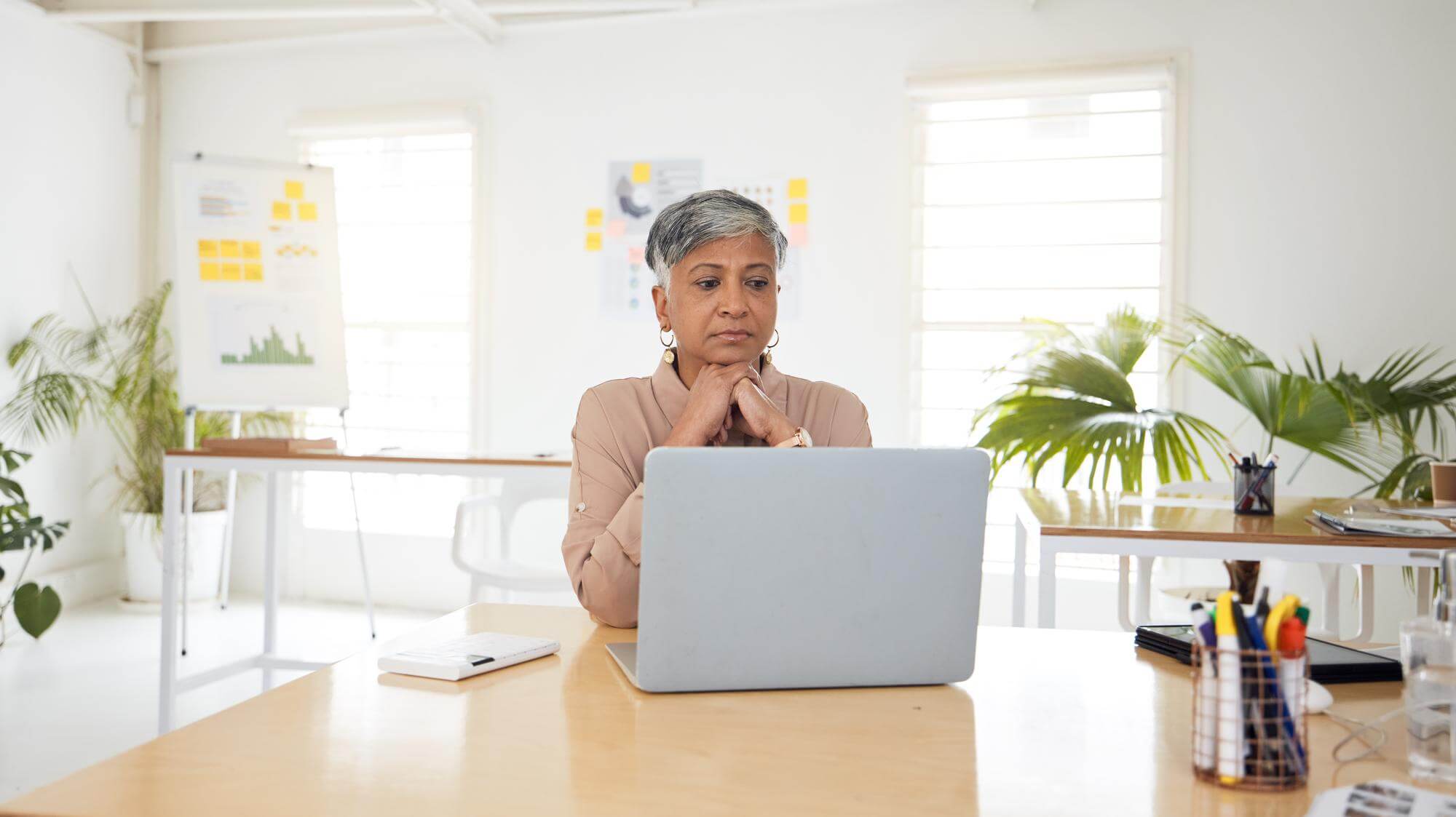 Mature Black woman at a bright office desk, hands folded, composed before a meeting